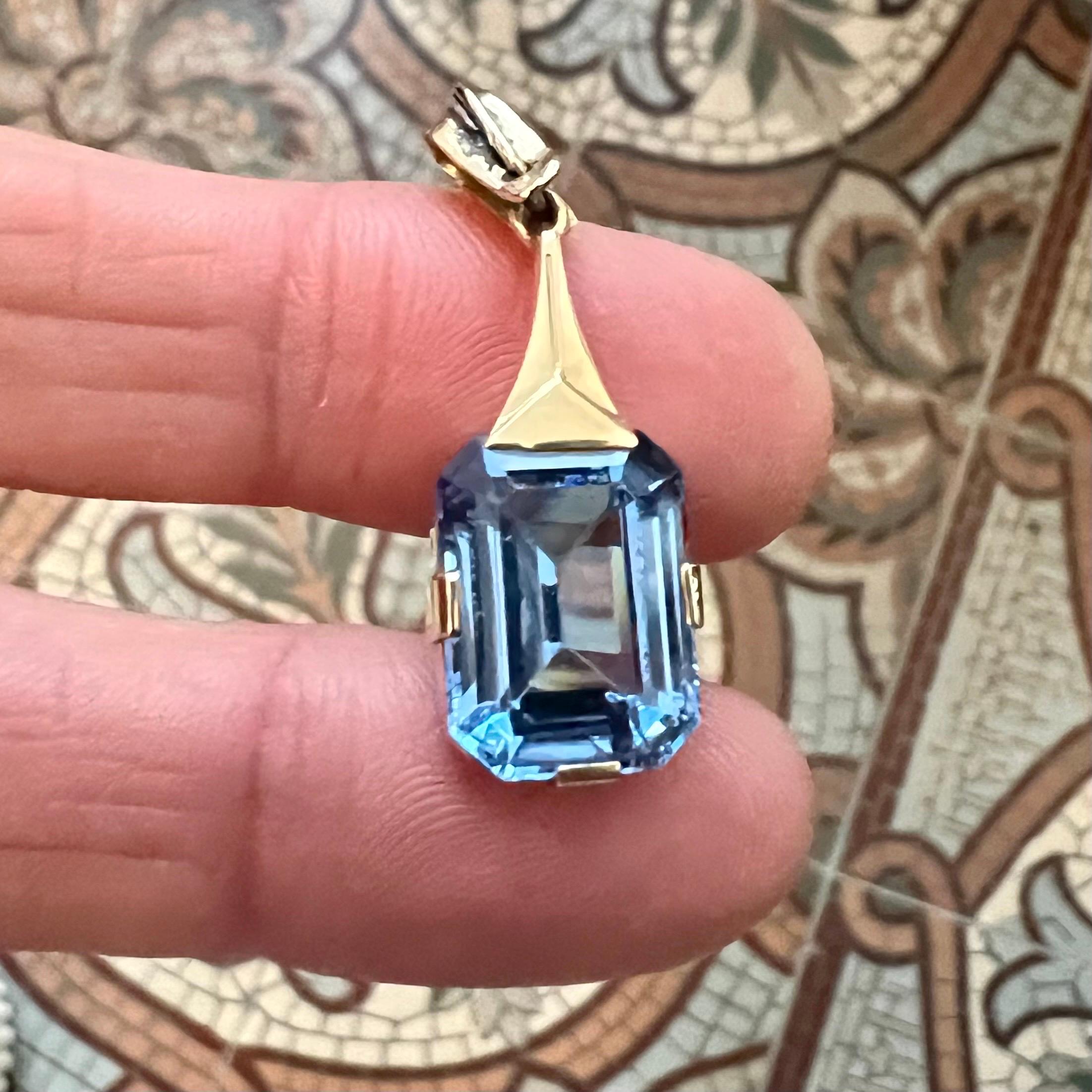 Questo splendido ciondolo vintage emana un'eleganza senza tempo grazie all'incantevole pietra di vetro color acquamarina incastonata nell'oro 14K. Il design bilancia perfettamente raffinatezza e charme, rendendolo un pezzo versatile sia per