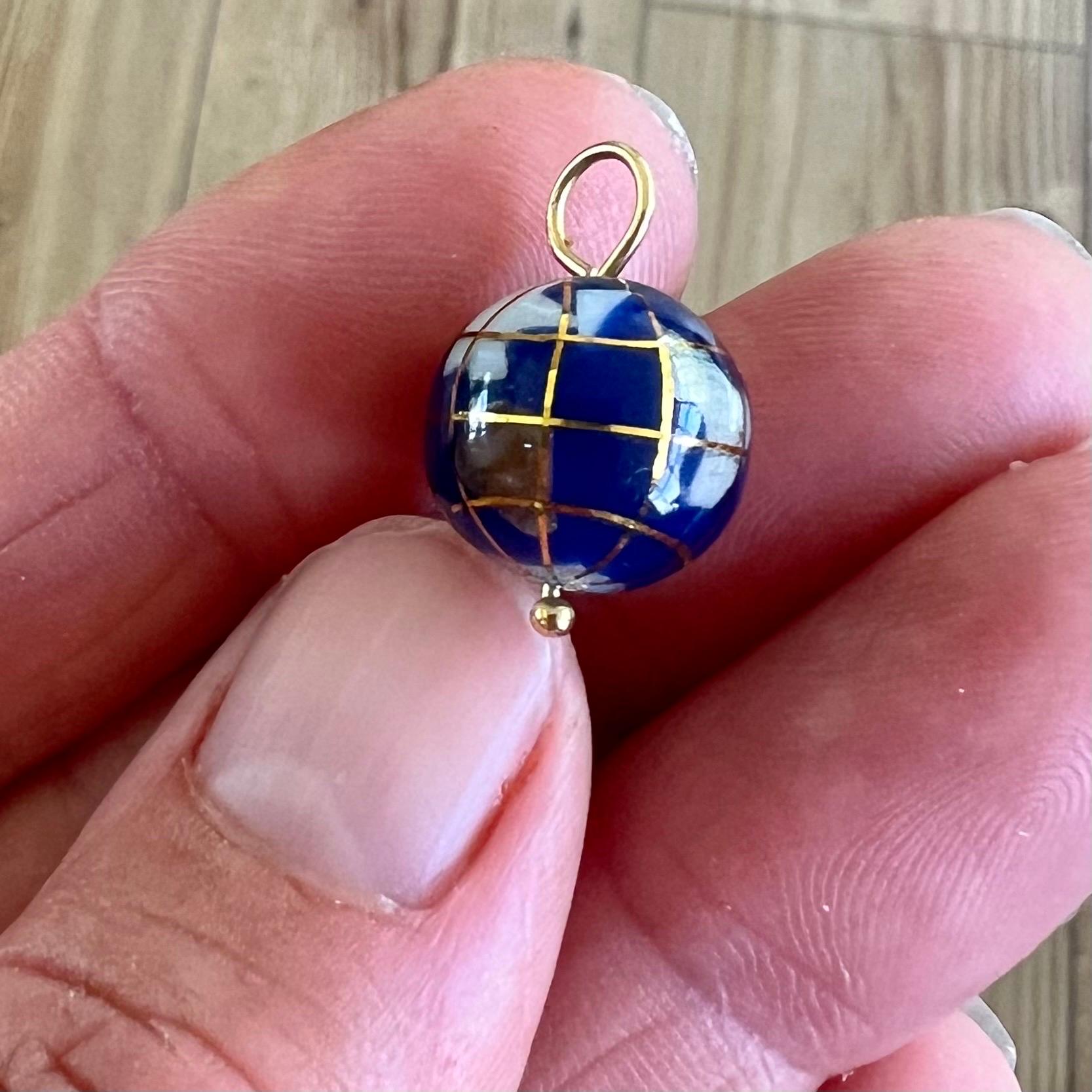Dieser exquisite kleine goldene Globus-Anhänger ist ein atemberaubendes Schmuckstück, das die Schönheit unseres Planeten in einem lebendigen und künstlerischen Design einfängt. Der Anhänger zeigt eine detailreiche Darstellung der Erde mit