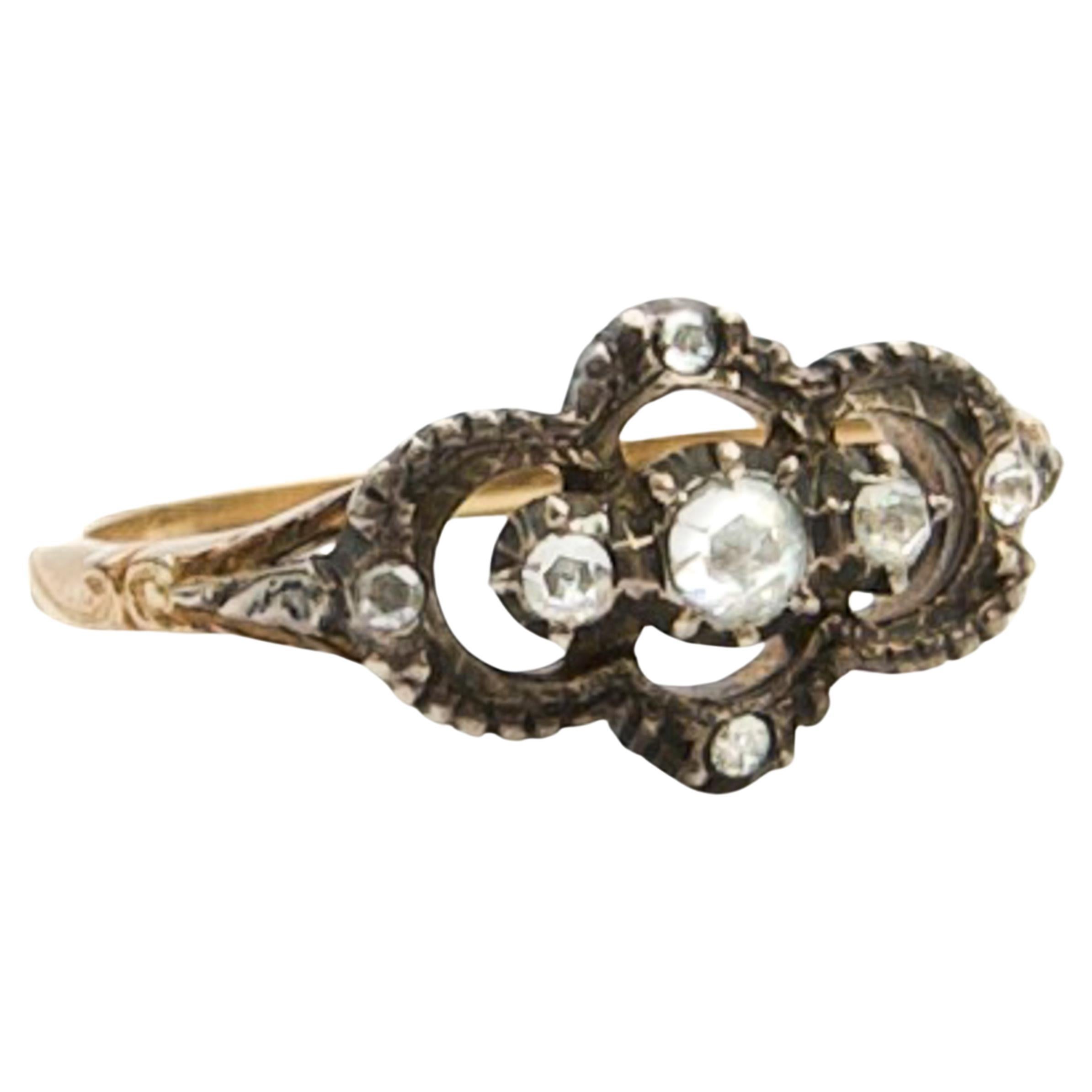 This 14 karat yellow gold ring has a silver front setting, set with 7 rose-cut diamonds in various sizes and set in closed, silver rubbed settings. The shank of the ring is made of 14 karat yellow gold and crafted with a beautiful engraving. The