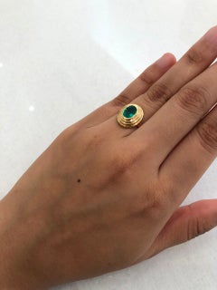 Bague moderne à l'émeraude ovale et à la lunette en or 18 carats