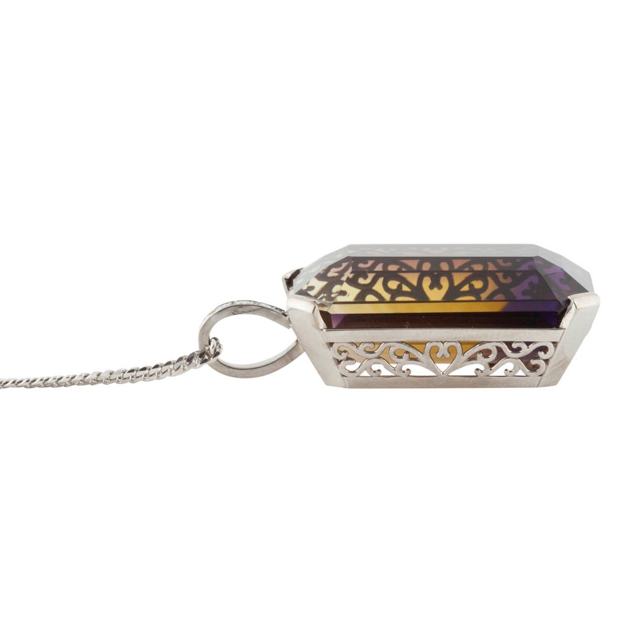 18ct white gold handcrafted pendant featuring a large rectangular Ametrine or Cognac Quart stone set above a decoratively scrolled and pierced white gold box mount joined to a looped bail, set to the front with 4 brilliant cut diamonds.
Ametrine