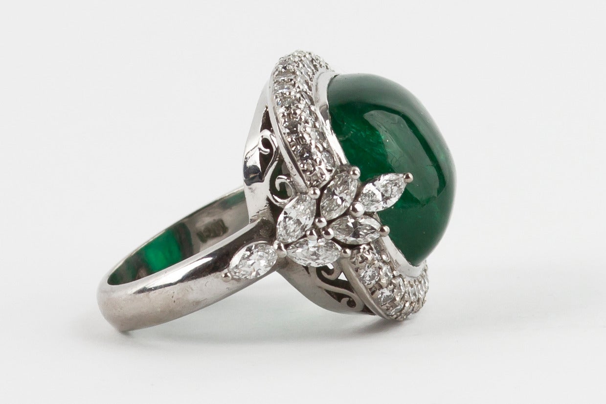 Stunning 18ct white gold cocktail ring set with a 13.50ct cabochon cut sugarloaf emerald surrounded by diamonds. The emerald is flanked by six marquise diamonds individually claw-set. Total diamond weight 1.75 carat, emerald 13.50 carat, graded in