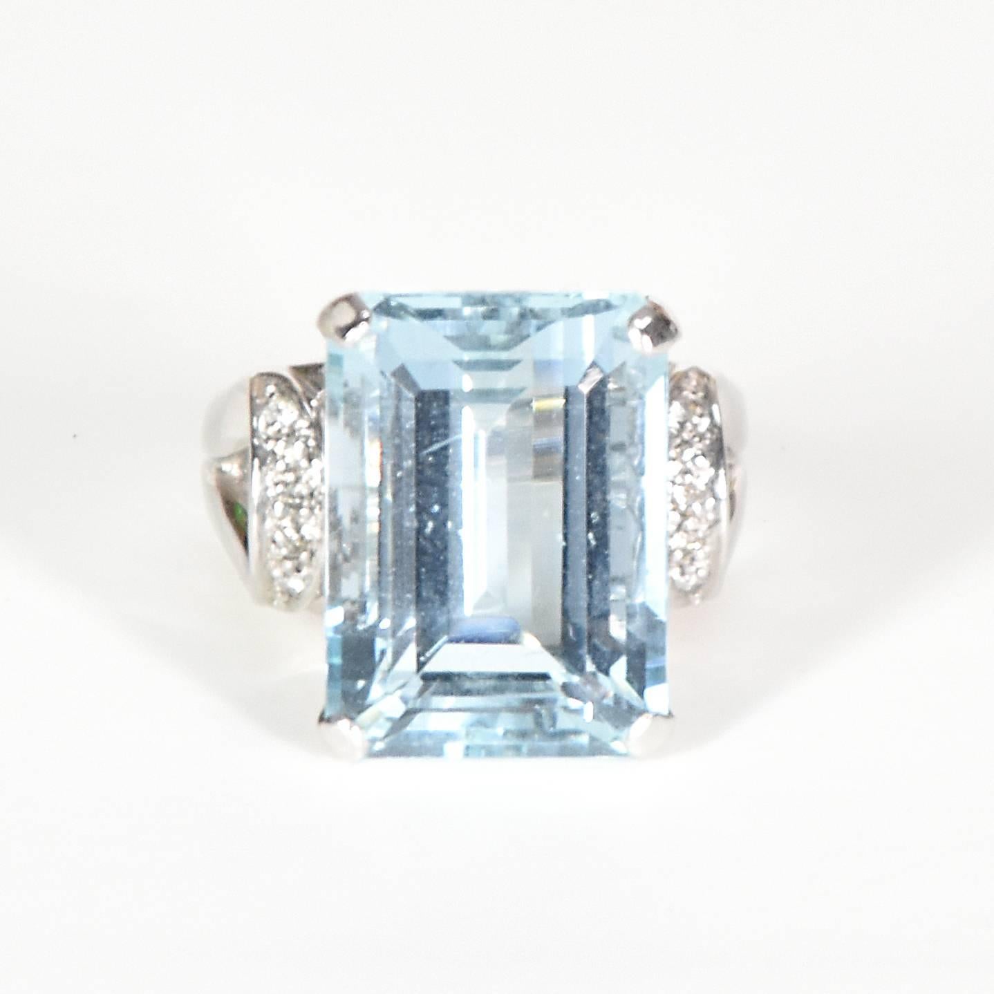 18ct white gold cocktail ring, featuring a large step-cut sky-blue coloured aquamarine, secured by 4 square claws of the geometrically pierced box mount joined to the divided under rails of the gallery above which the looped shoulders are located,