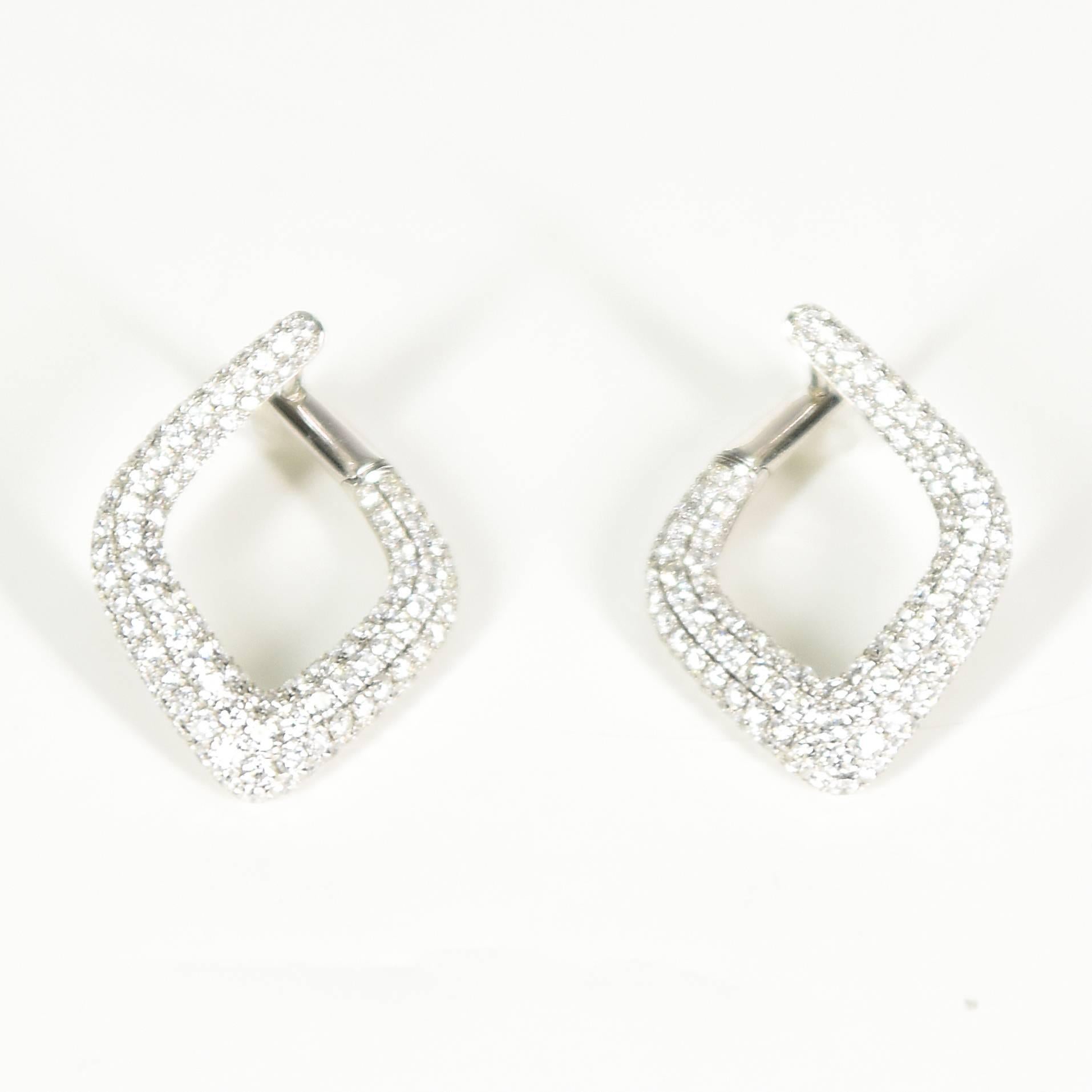 A pair of Modernist 18ct white gold, diamond-set, open-centred rhomb shaped hoop earrings. Each earring is micro-claw set with 135 brilliant cut diamonds, all totalling 3.35ct. Enclosed to the back by decoratively pierced under rails. 
Calculated