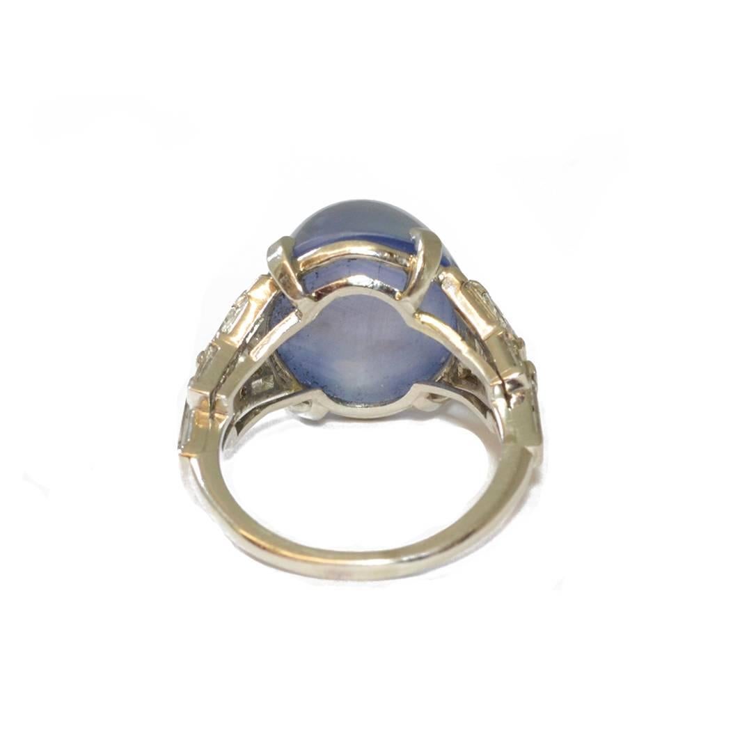 An Art Deco star sapphire ring, the high blue/grey cabochon flanked by diamond set shoulders. Mounted in platinum.
Ring size O 1/2 
