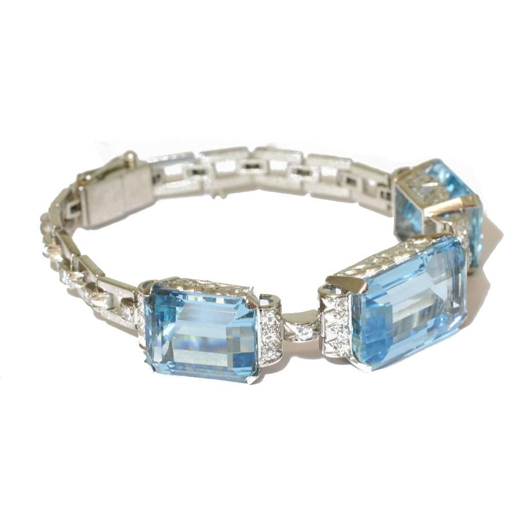 A bracelet set with three emerald cut aquamarine diamonds edged with diamonds, mounted in platinum. The rectangular open links are further accented by diamonds. American, circa 1950.