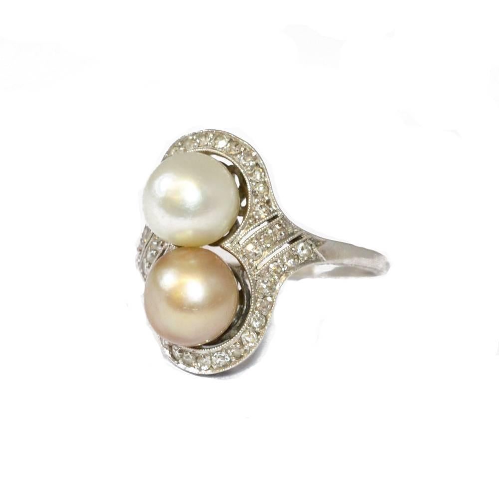 A natural Oriental pearl and diamond ring, with one golden pearl and one white pearl surrounded by a diamond set border. Mounted in platinum. American circa 1915
Ring size L 1/2 