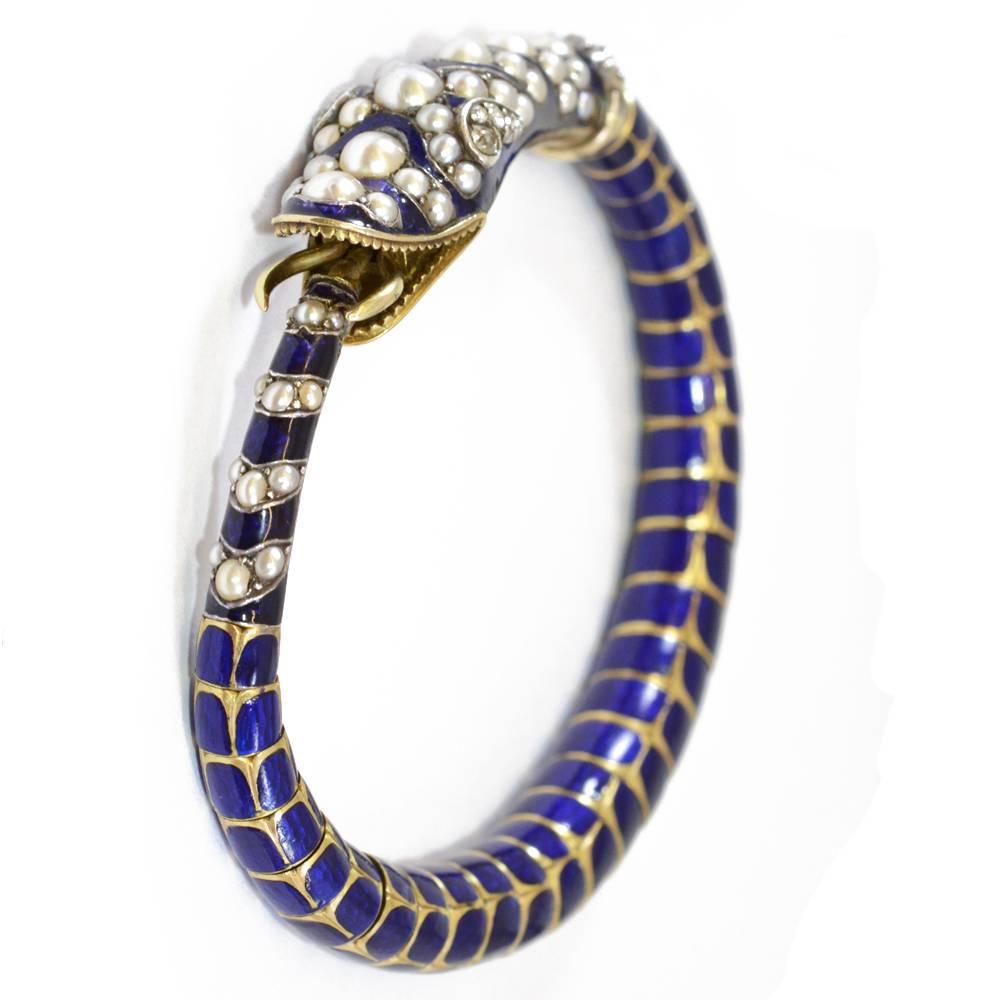 A Victorian snake bangle in the form of an ouroboros, with blue enamel decoration, and set with diamonds and pearls. Mounted in yellow gold. English, circa 1880.