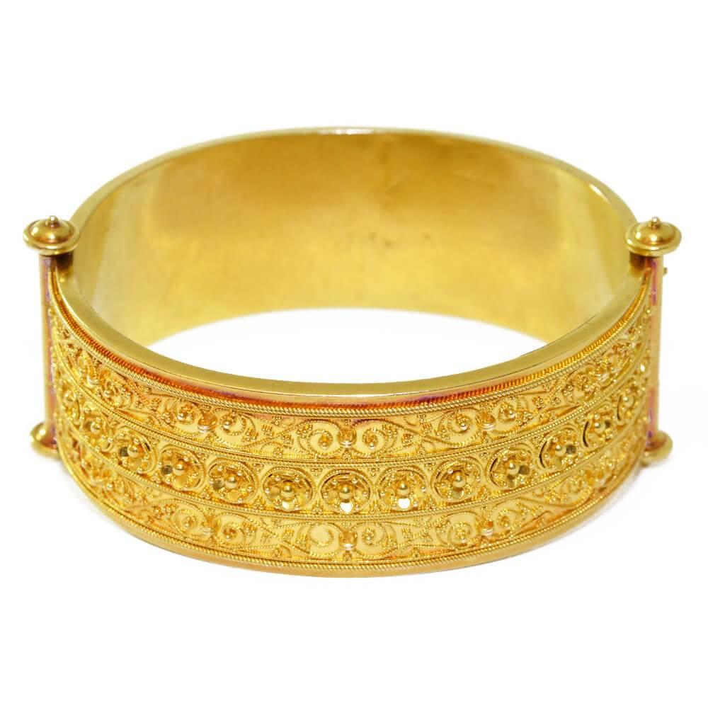 A Victorian Etruscan Revival hinged bangle, decorated with granulation and cannetille work with  a different pattern on each side. English, circa 1865.