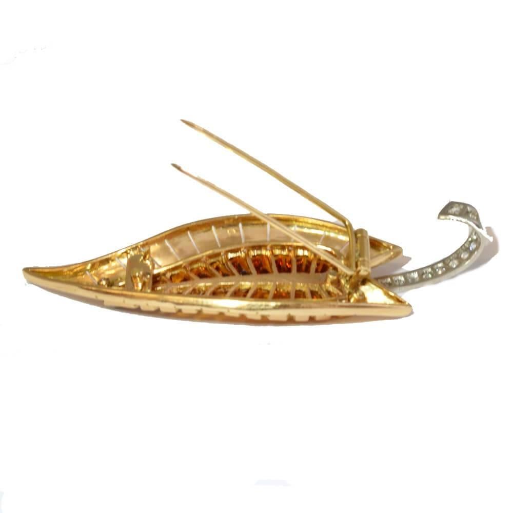 A stylised brooch in the form of a leaf, set with calibre cut citrines with a curved diamond stem running the length of the pin. Mounted in 18ct yellow gold and platinum. Signed Cartier Paris. Circa 1930.