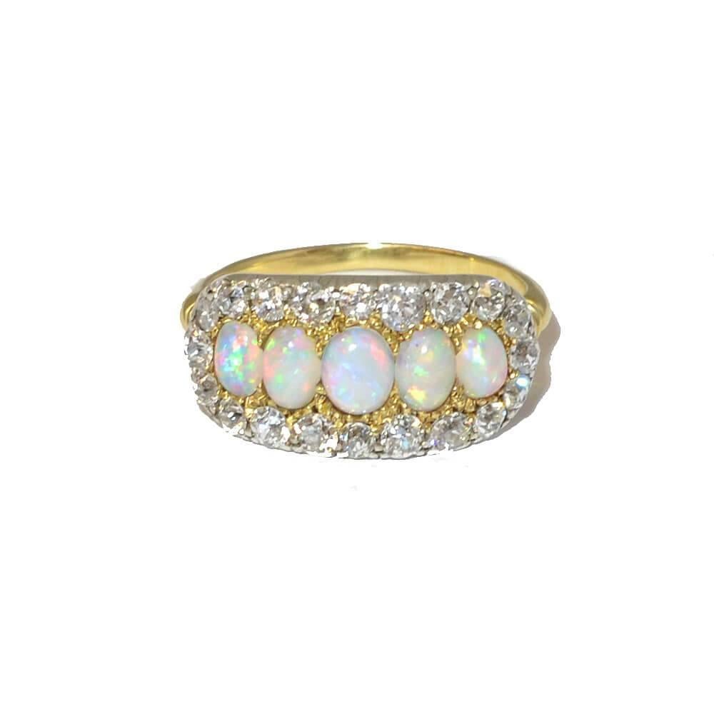 A Victorian five-stone white opal and diamond cluster ring. The graduated oval opal cabochons are surrounded by a row of old cut diamonds. Mounted in 18ct yellow gold and silver. English, Circa 1880.