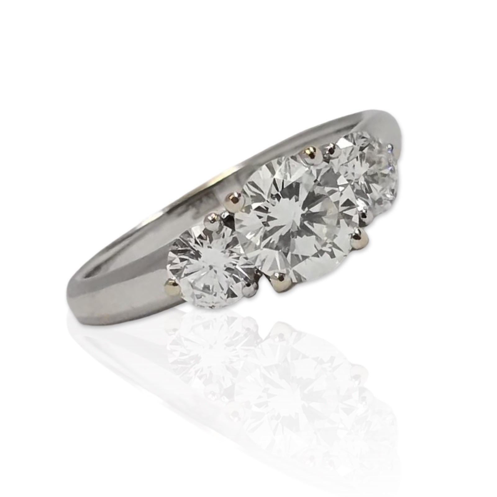 Cette élégante bague à trois pierres est réalisée en or blanc 18 carats et met en valeur un trio de diamants ronds de taille brillant certifiés GIA d'un poids combiné d'environ 1,55 carat. Les diamants sont presque incolores, transparents et
