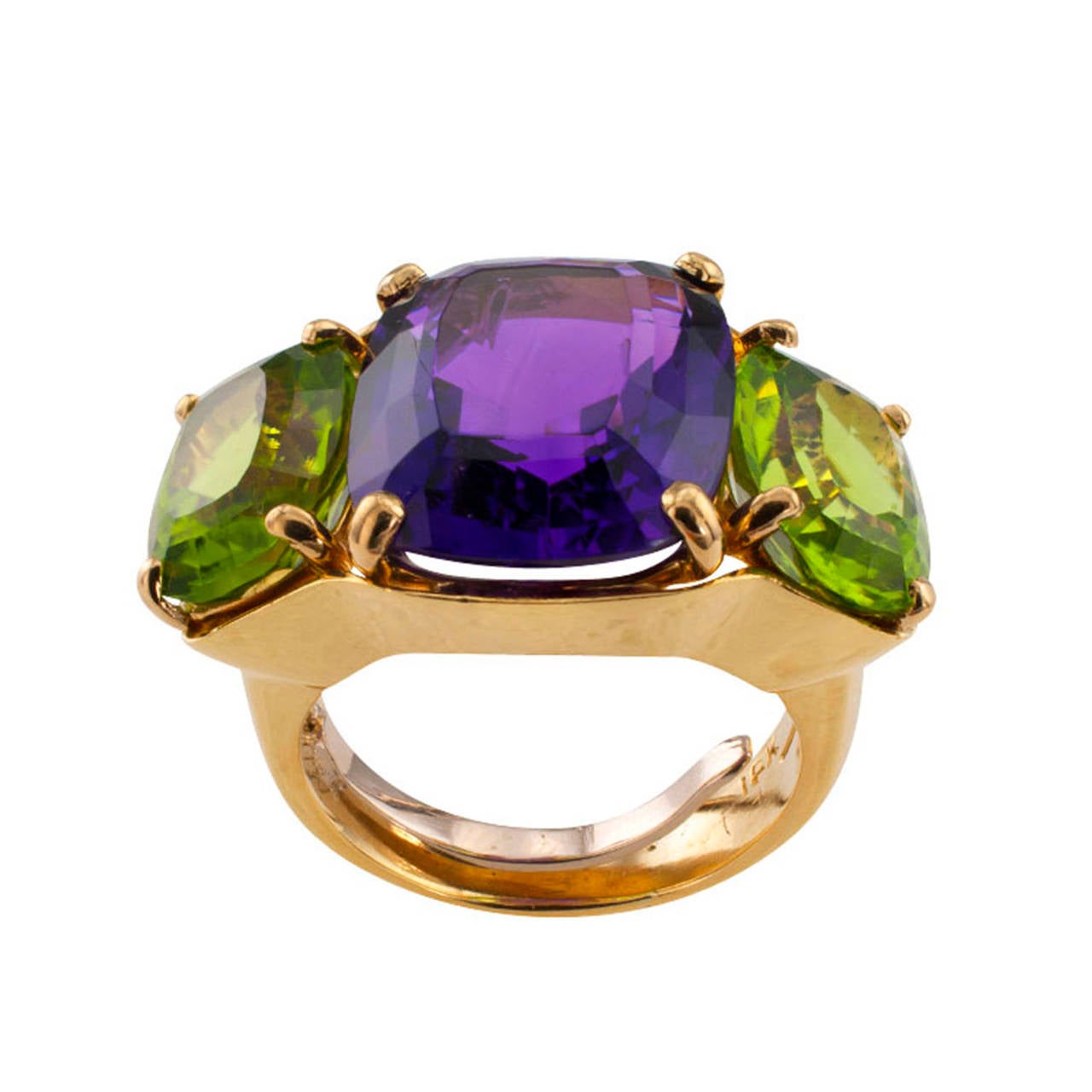Elegant and bold with a lavish display of rich intense colors, this large designed ring features a trio of cushion-shaped gemstones, an amethyst between a pair of peridots, mounted in 18 karat gold, approximately 5/8