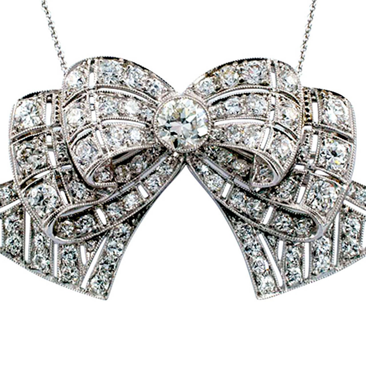 Art Deco brooch, circa 1925.  Combining opulence and grace, the double bow design is knotted by a single larger diamond.  With open work and milegrain design, sparkling ribbons are set with smaller diamonds.  Eighty-nine fine diamonds in all,