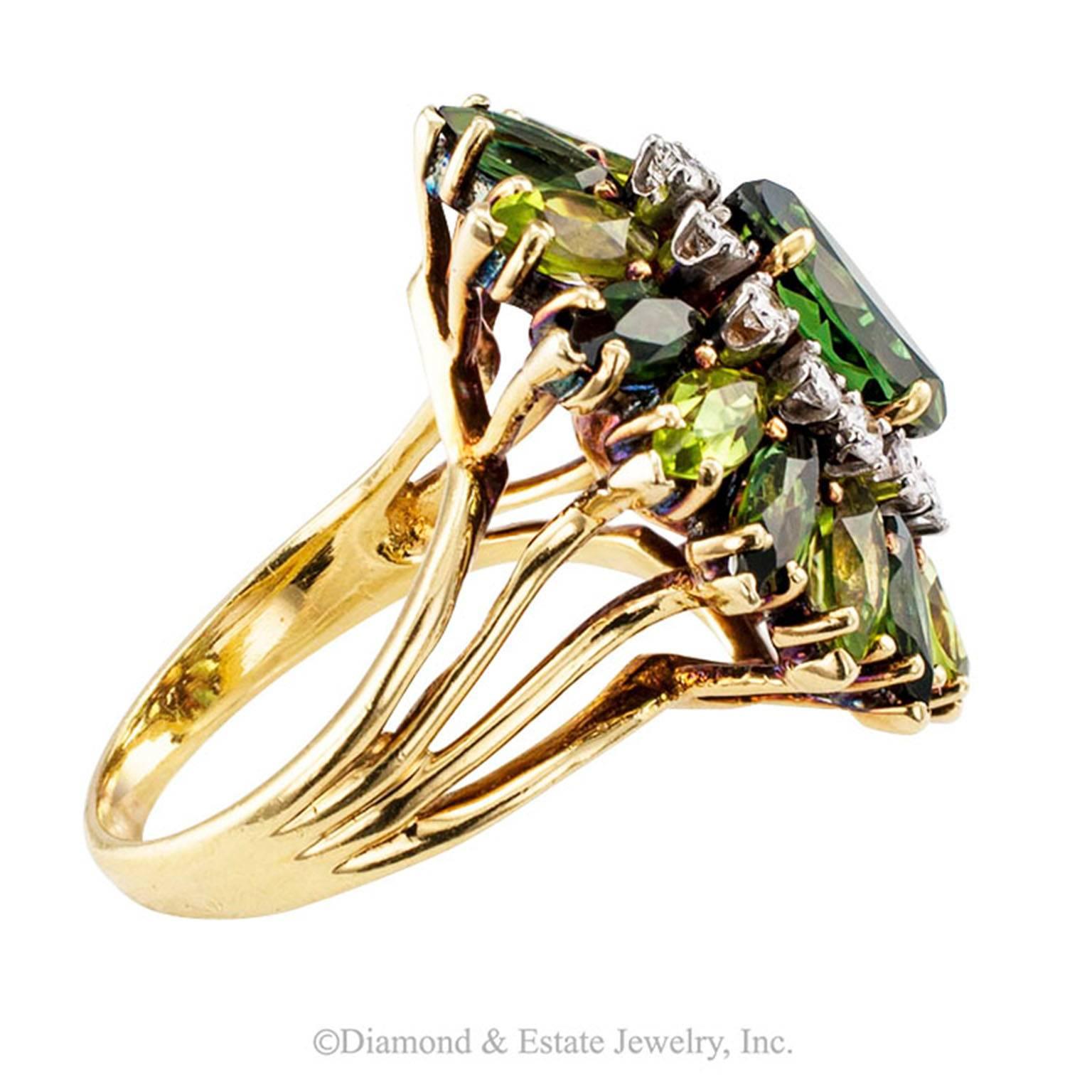 Green Tourmaline Diamond Cocktail Ring
1970s Marquise shaped green tourmaline and round brilliant-cut diamond ballerina 18 karat yellow gold ring.  Centering upon a larger marquise green tourmaline within a conforming border comprising twelve round