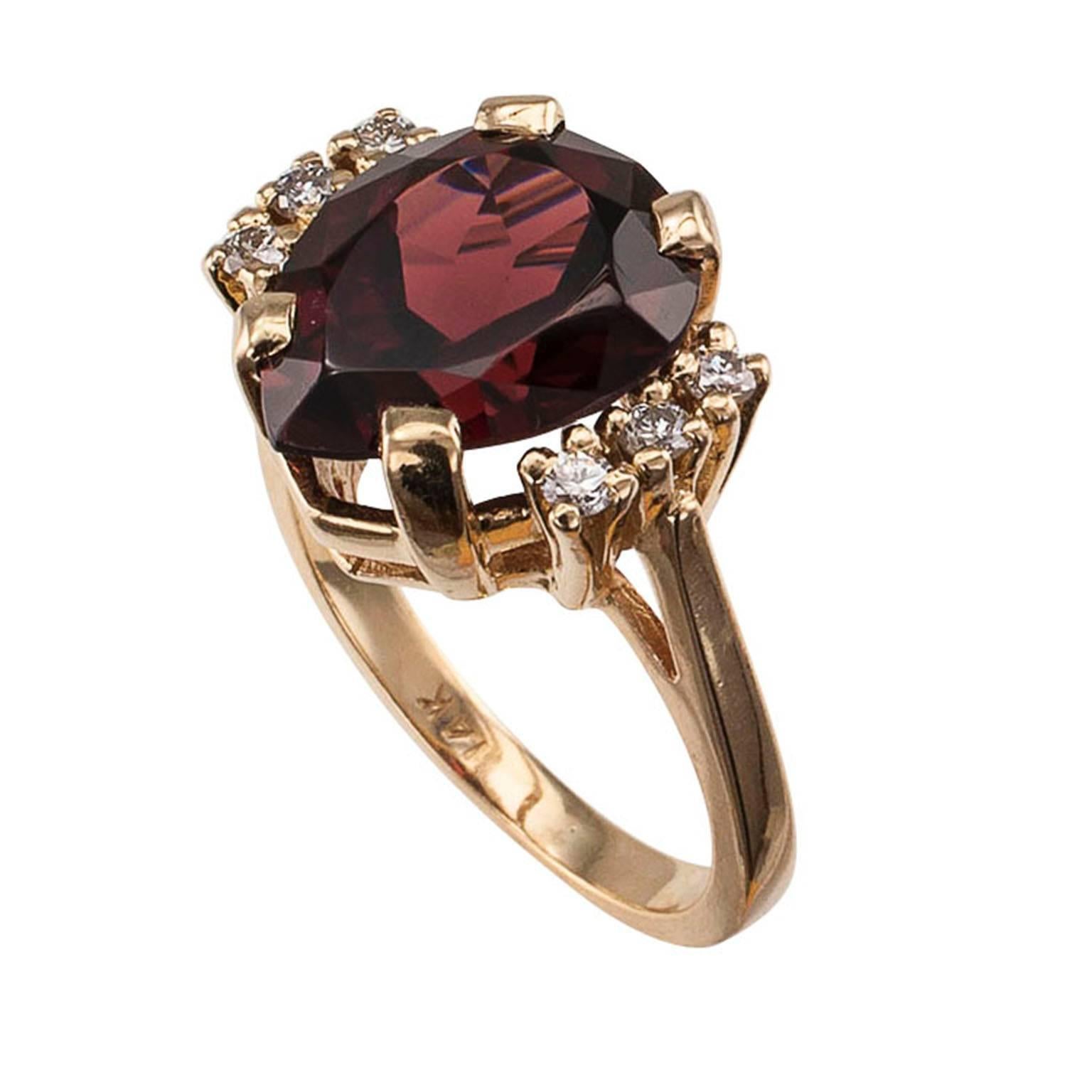Garnet Diamond Gold Ring

Garnet and diamond gold ring circa 1980.  A teardrop-shaped garnet weighing approximately 6.50 carats has the starring role in this charming ring.  With its extremely pleasing color reminiscent  of a fine claret wine, it