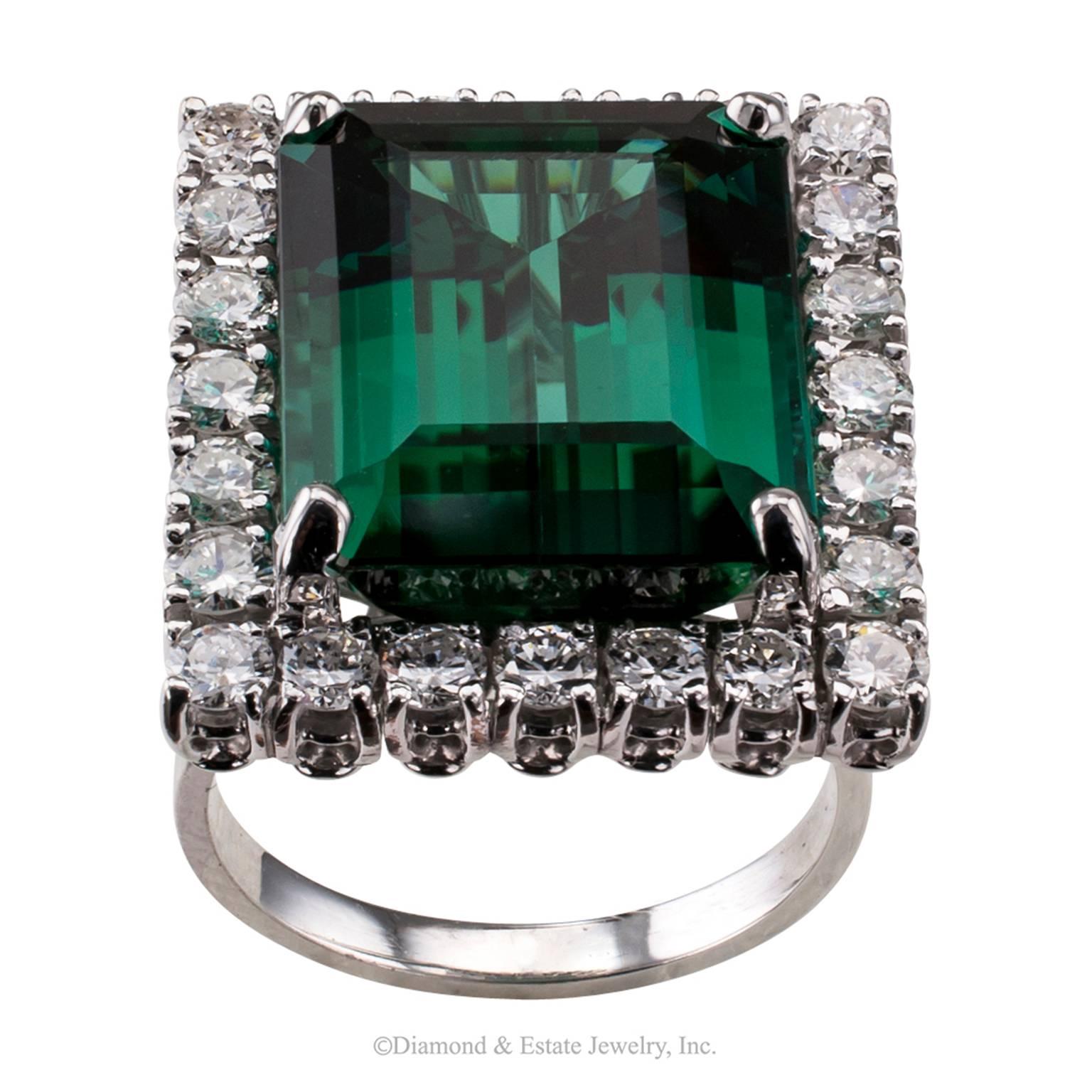 1960s Emerald-cut Blue-green Tourmaline Diamond Cocktail Ring

This ring is set with an incredible 15.04 carats emerald-cut blue-green tourmaline surrounded by diamonds set in this hand made 14-karat white gold setting, circa 1960.  The 15.04 carats