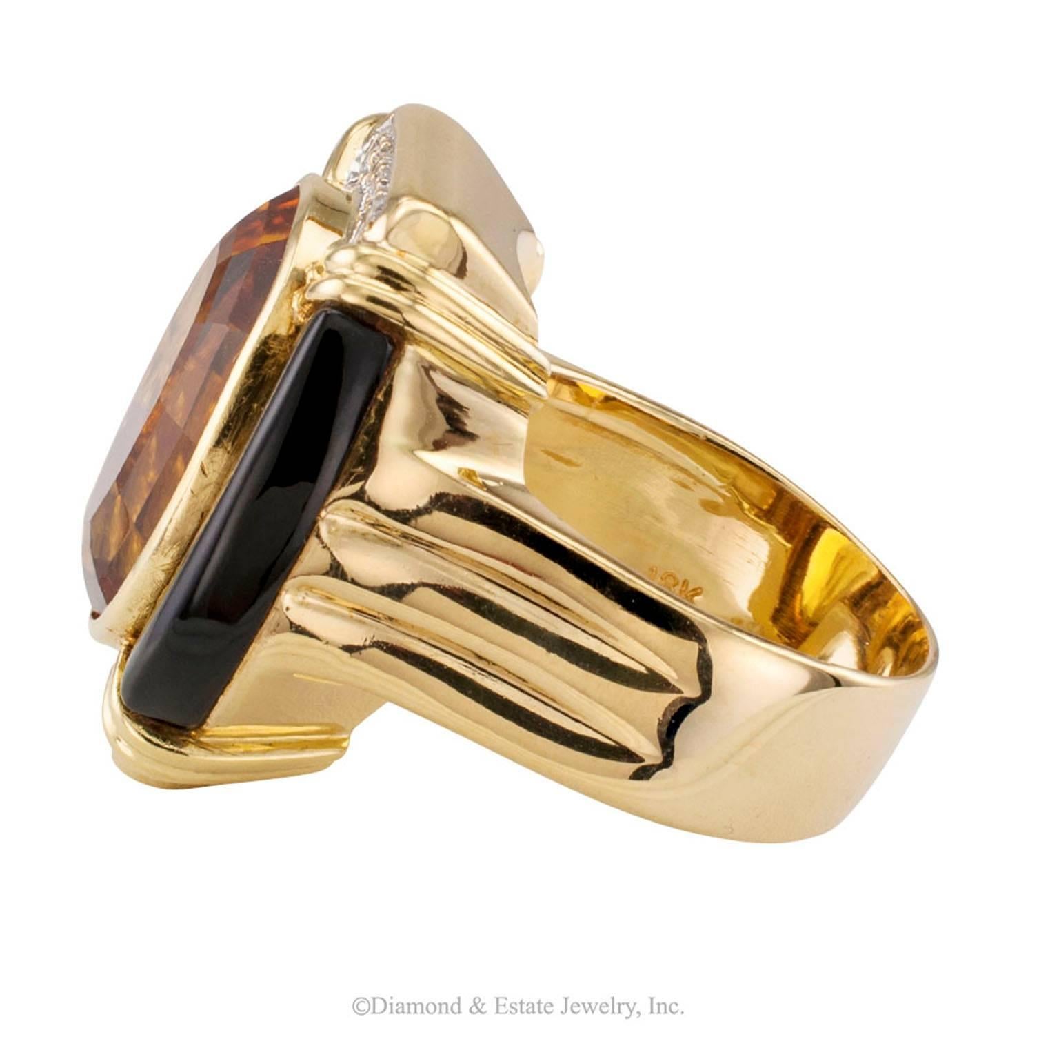 1980s Citrine Onyx Diamond Gold Ring

Citrine onyx and diamond gold cocktail ring circa 1980.  The larger oval citrine within a bold split frame formed by tubular black onyx caps set with diamonds to the horizontal planes, all on top of a