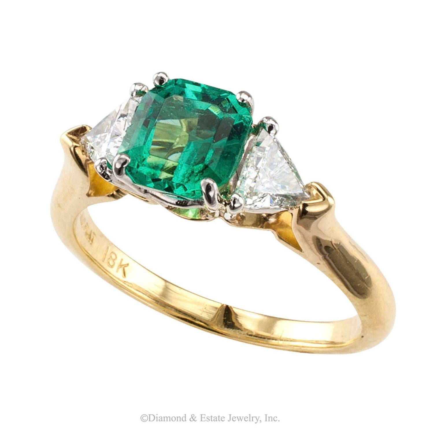 Emerald Diamond Three Stone Gold Platinum Ring

Three-stone emerald and diamond ring mounted in 18-karat gold and platinum.  The cushion-cut Colombian emerald taking center stage weighing approximately 1.00 carat, between a pair of trilliant-cut
