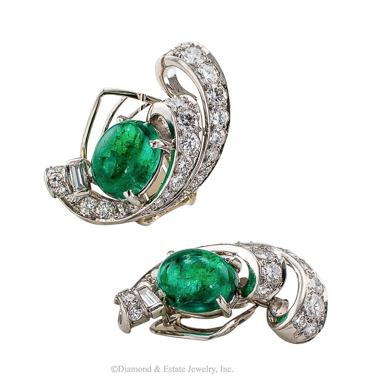 1930s Emerald Diamond Platinum Ear Clips

1930s cabochon emerald diamond and platinum button ear clips.  Featuring a pair of jelly bean like cabochon emeralds together weighing approximately 4.75 carats, nestled in between open scrolling motifs set