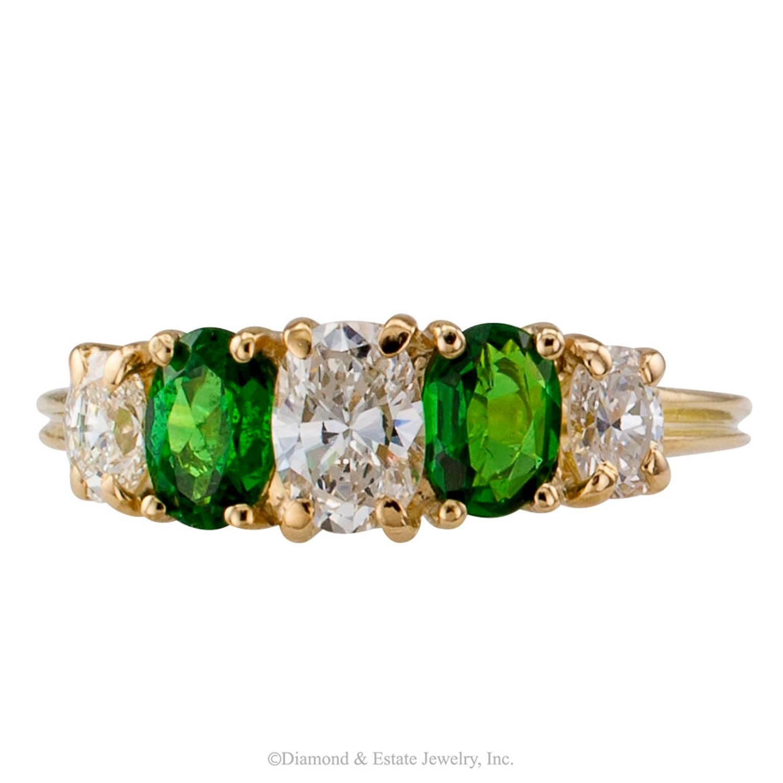 Tsavorite Garnet Diamond Gold Five-stone Ring

Tsavorite garnet and diamond five-stone gold ring circa 1980.  The design features a pair of beautiful and bright oval tsavorite garnets weighing approximately 0.67 carat, spaced between three similarly