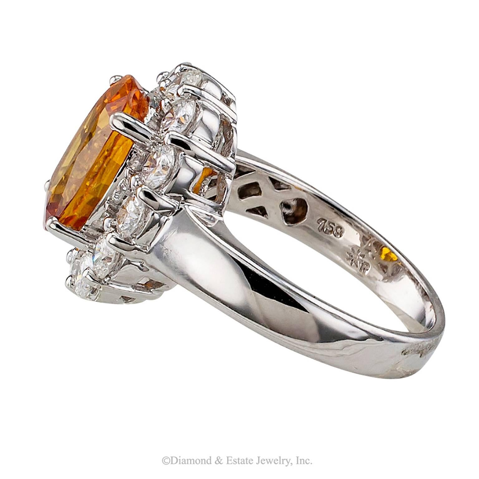 Orange Sapphire Diamond Gold Ring

Orange sapphire 4.75 carats set in an 18 karat white gold and diamond ring circa 1990.  Centering upon a bright orange colored oval sapphire weighing 4.75 carats, within a conforming border of round brilliant-cut