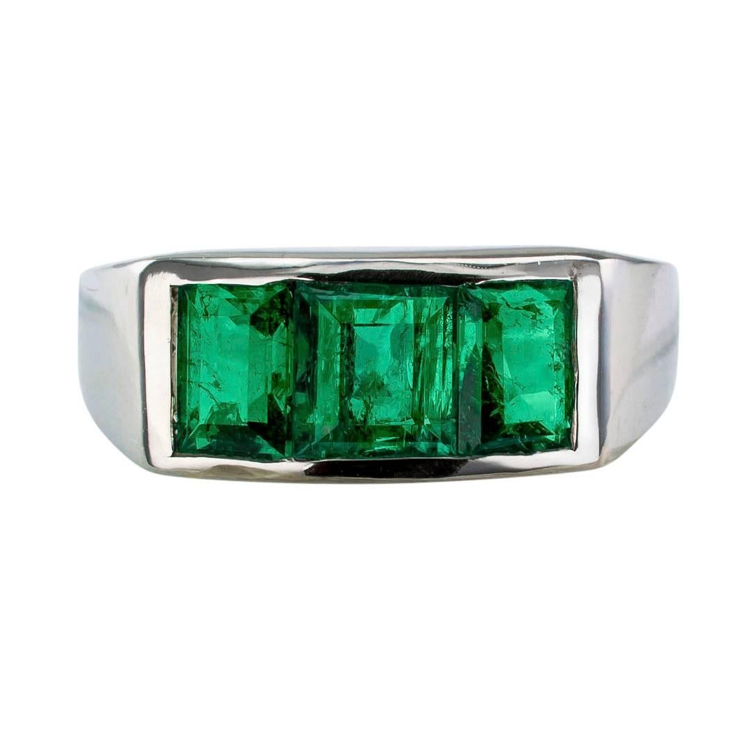 1940s three stone Colombian emerald and platinum ring. The design features three rectangular-cut Colombian emeralds totaling approximately 1.75 carats, channel set on a simple, low profile and substantial platinum mounting. This, in every respect,