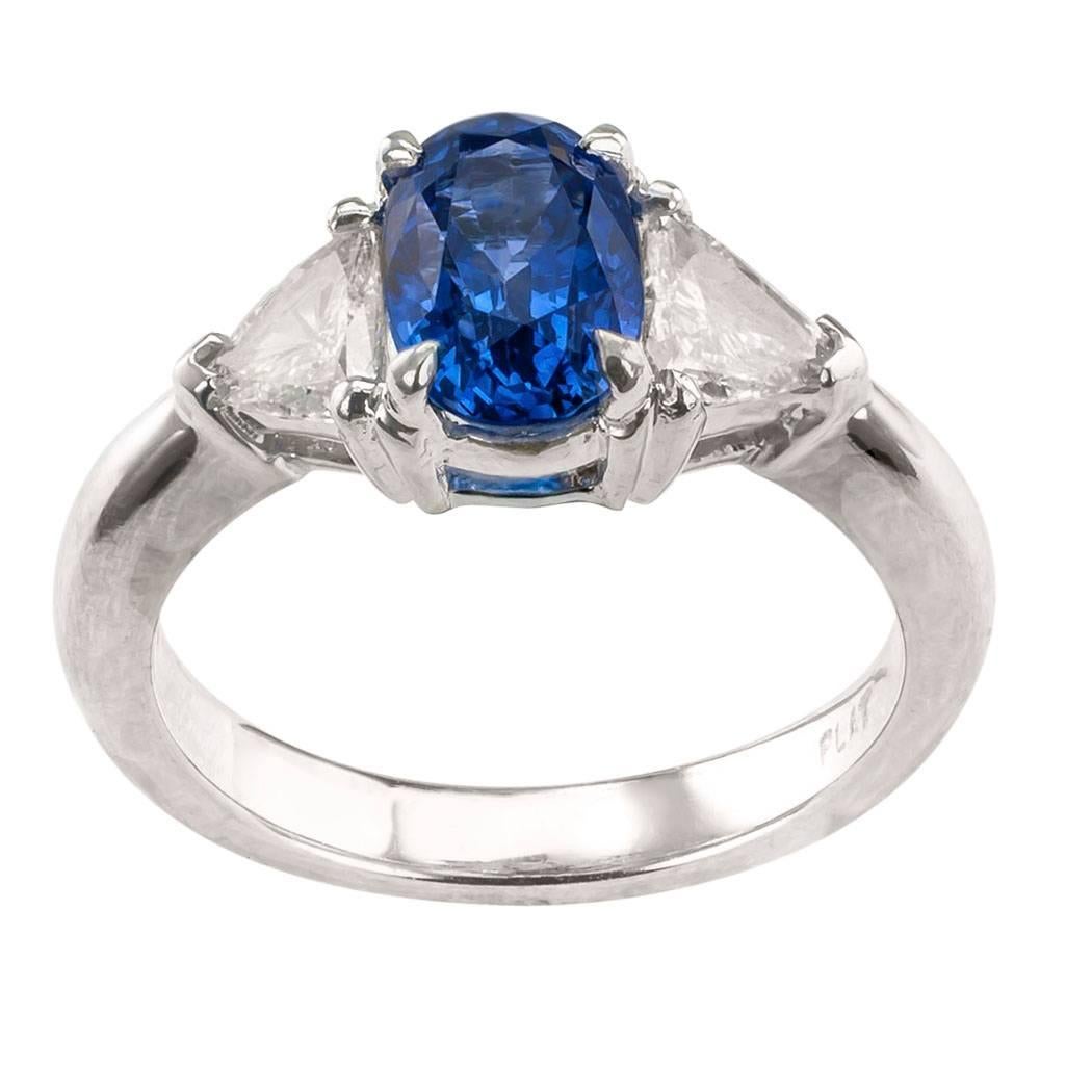 Sapphire and diamond three stone platinum ring circa 1990. An oval blue sapphire weighing 1.78 carats set between a pair of triangular-cut diamonds totaling approximately 0.50 carat, approximately H color and VS clarity, mounted in a strong and