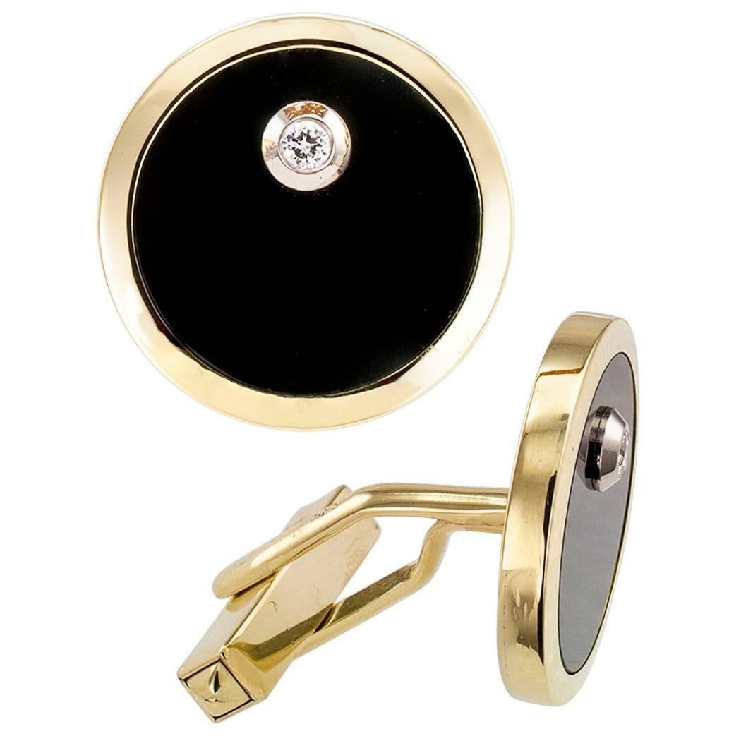 1960s black onyx diamond and gold cuff links. Featuring a pair of bezel-set black onyx discs, each studded with a similarly-set round brilliant-cut diamond, together weighing approximately 0.07 carat, mounted in 14-karat yellow gold with ergonomic