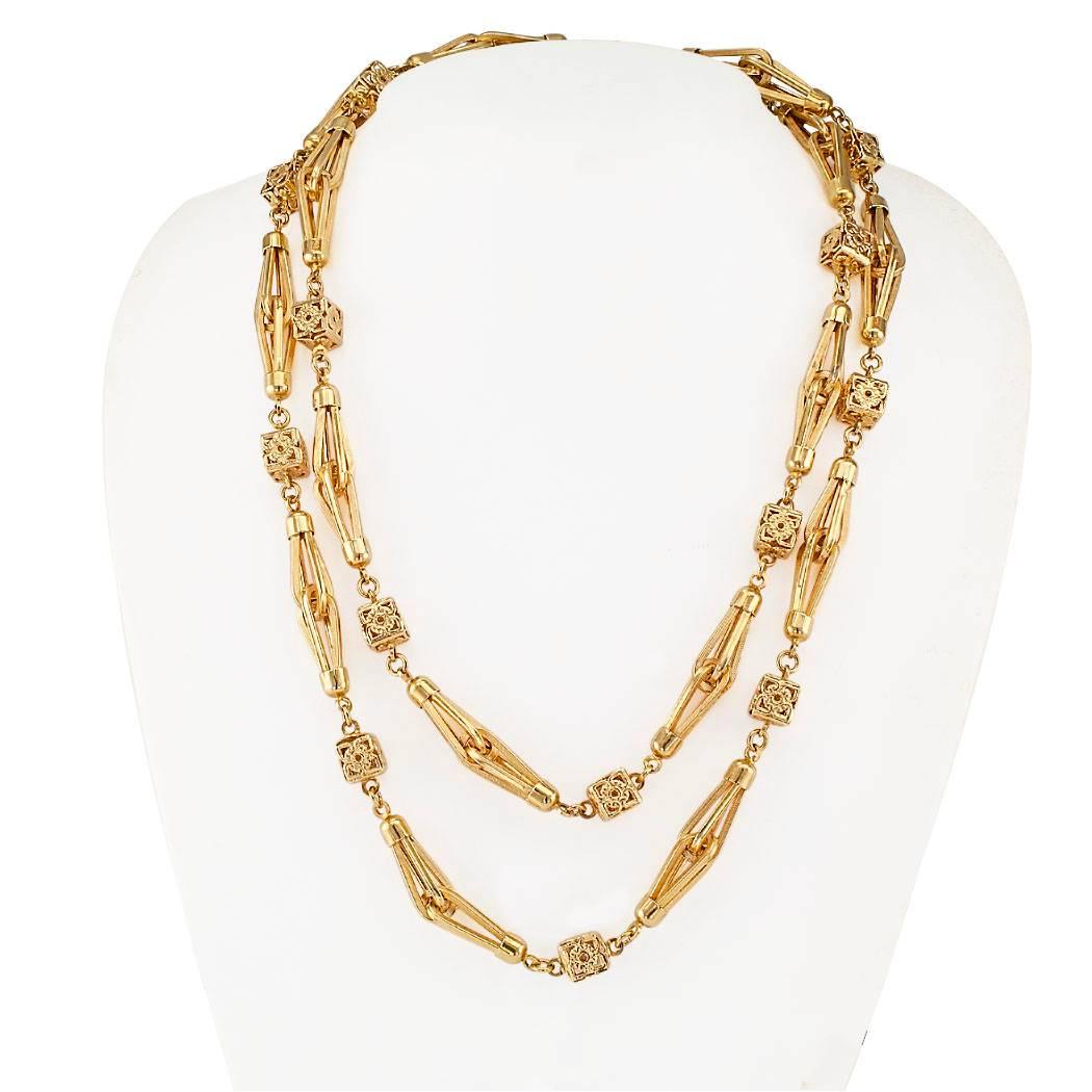 1960s Italian gold long chain. The 18-karat yellow gold open work design features entwined teardrop shaped links between cubic connectors forming a thirty-eight inch long voluminous and fluid long chain that is pleasing to the senses and makes a