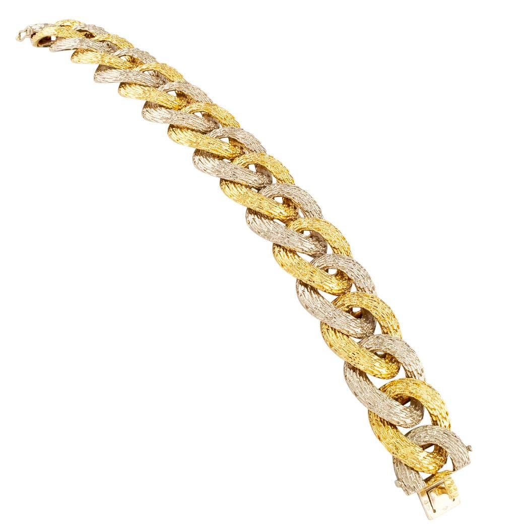 French 1980s two-tone curbed link gold bracelet. The chunky design features alternating yellow and white, textured 18-karat gold links composing what amounts to a striking and elegant bracelet that feels luxurious on the wrist and is delicious to