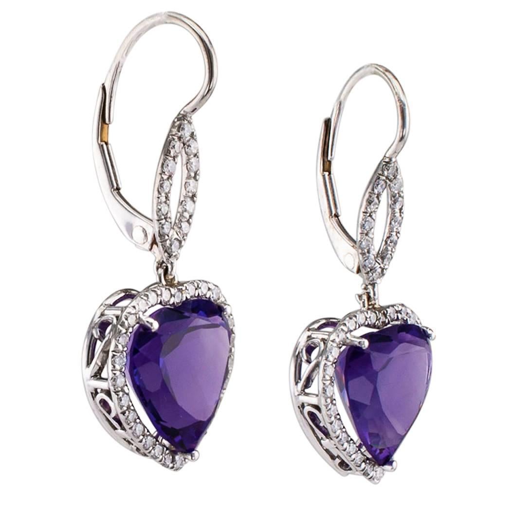 Heart shaped amethyst and diamond platinum and white gold earrings. The swinging designs showcase a pair of richly colored heart-shaped amethyst weighing 7.75 carats, within conforming diamond frames, suspended from open, navette-shaped diamond