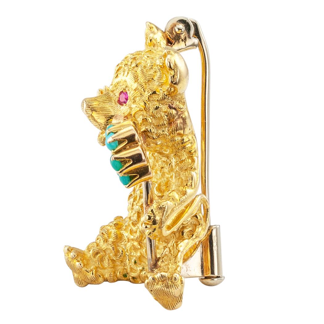 Cartier ruby turquoise and gold teddy bear brooch circa 1960. The smiling teddy bear waves his right paw while holding a turquoise and ruby flower with his left, ruby-set eyes, his 18-karat gold body textured in such a way that he appears to be soft