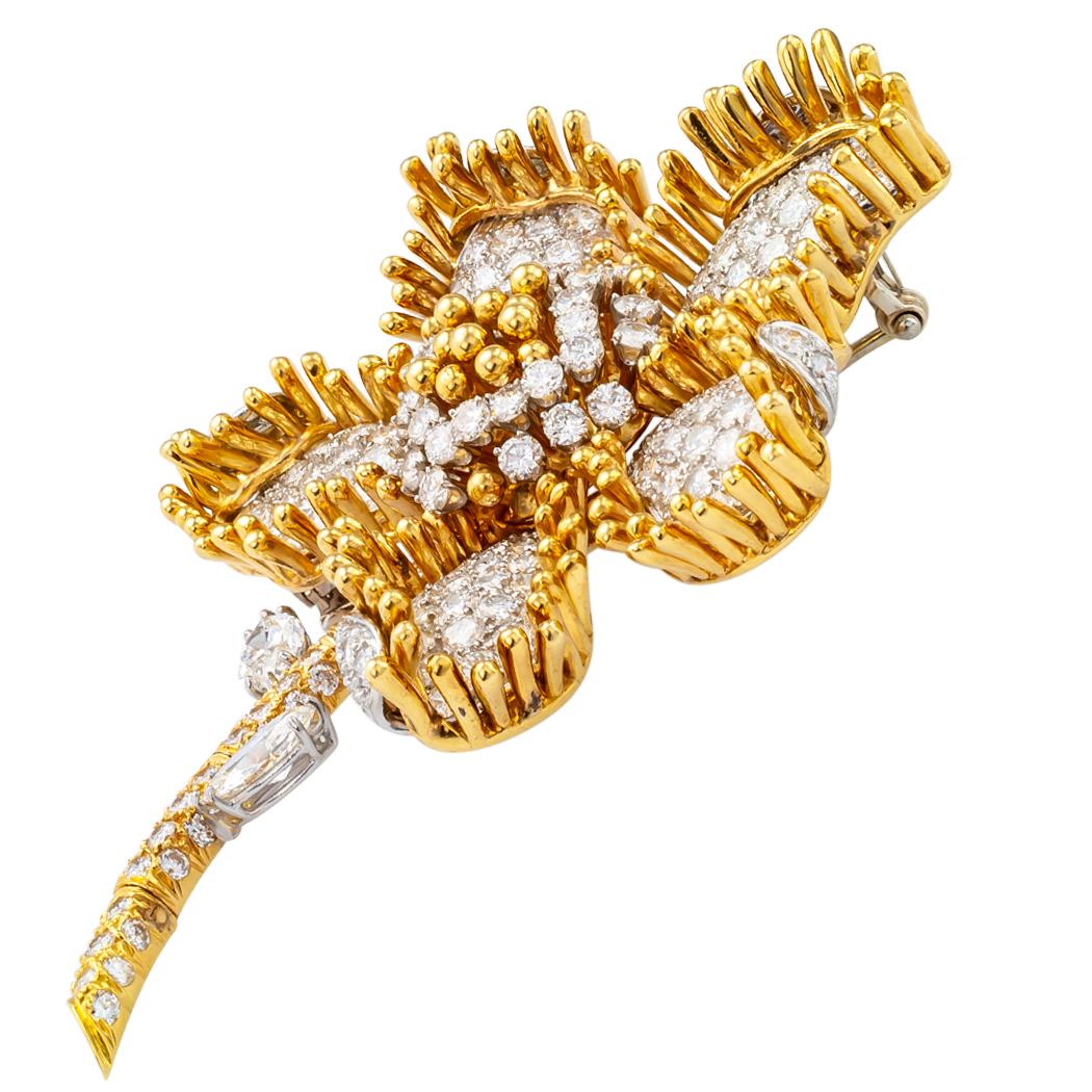 Diamond flower clip/brooch mounted in 18 karat gold and platinum circa 1970. The graceful five-petal flower design features a slightly articulated stem. The flower head itself displays its opulence on a grand scale with approximately 11.50 carats of