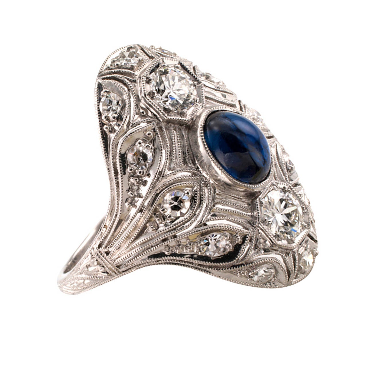 An oval cabochon sapphire bezel set between a pair of old European-cut diamonds set to the-north-and-south are the center of attraction in this beautiful domed Art Deco dinner ring.  Twelve smaller single-cut diamonds add extra sparkle too, nestled