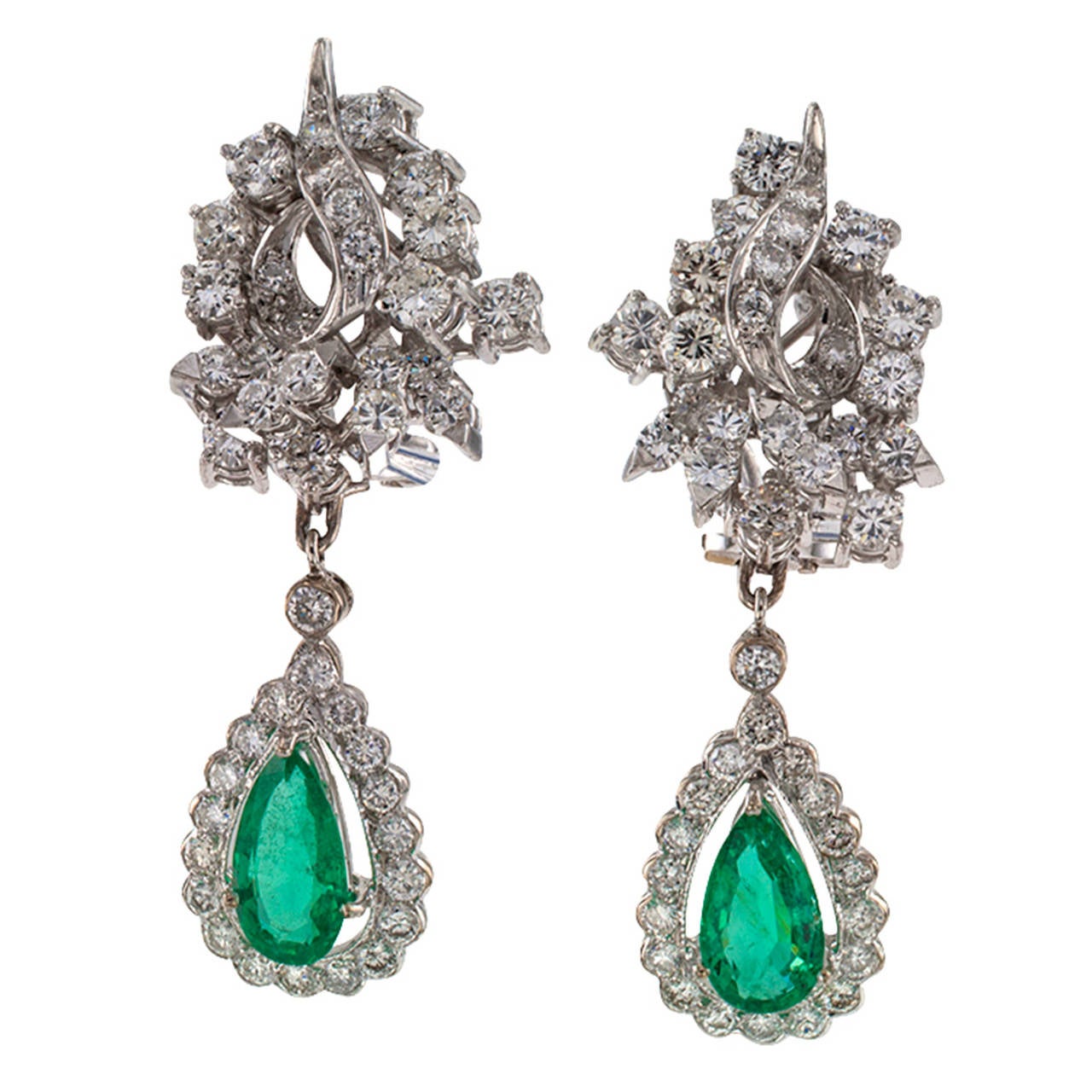 Emerald Diamond Gold Earrings

The articulated surmounts are designed as elegant and sculptural scrolling motifs that are literally brimming with sparkling round brilliant-cut diamonds, showcasing, within their conforming and pendent diamond