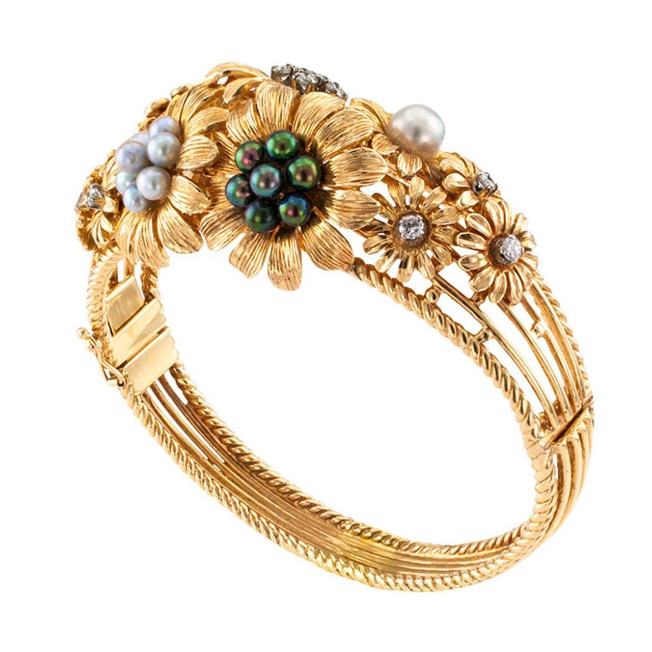 A rare and unusual hinged bangle design design embellished on the top half with a spray of graduating exotic flowers, each flower centering clusters or single cultured pearls of various shades of color or diamonds in similar configurations, thirteen