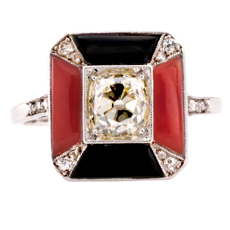 This elegant and refined rectangular art deco ring is set with an old Old mine cushion-cut diamond weighing approximately 0.75 carat ( VS clarity, light yellow color)  highlighted by very striking parallel coral and black onyx  stones, between small