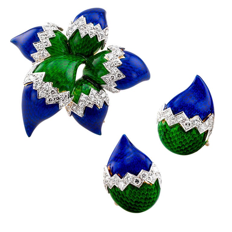 Designed as an exotic flower with teardrop-shaped petals decorated with translucent emerald green and royal blue enamel over machined gold, with diamond accents totaling 2.25 carats, approximately H - I color and VS clarity, mounted in 18 karat