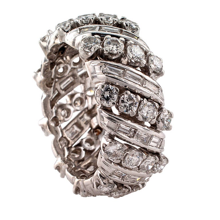 Circa 1950, anyone who likes a wide diamond wedding band will appreciate this beautiful 10 mm wide platinum eternity ring featuring rows of prong-set round brilliant-cut diamonds alternating with channel-set baguette diamonds, all totaling