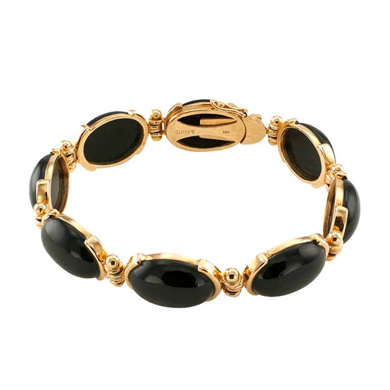Circa 1980, the basic black and very classic estate design comprising a series of links featuring black jade oval cabochons set in half bezels, joined from the ends by hinged links, 14 karat gold, signed Gumps on the clasp, 7