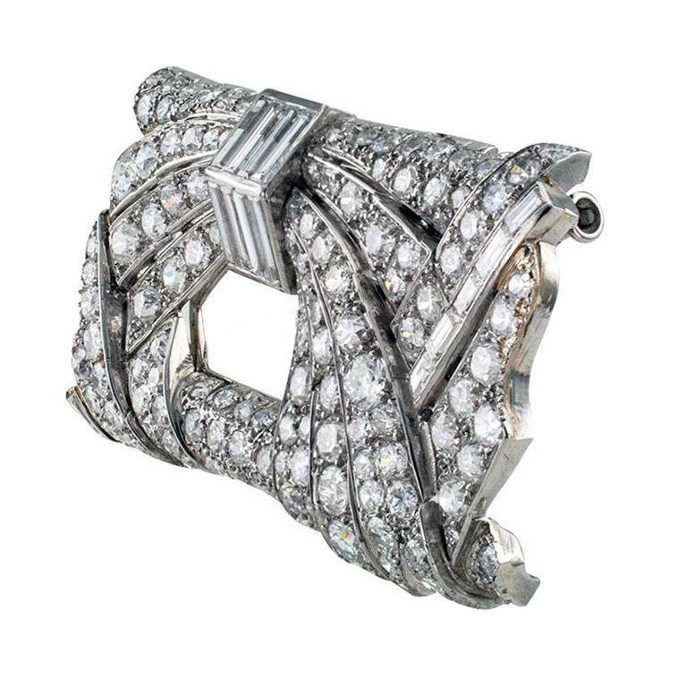 This unique French Art Deco design is composed by a bold rectangular motif filled with courses of round diamonds gently cascading around a central opening juxtapositioned with baguette diamond motifs, the look is tres avant-garde, 100% Diva. There