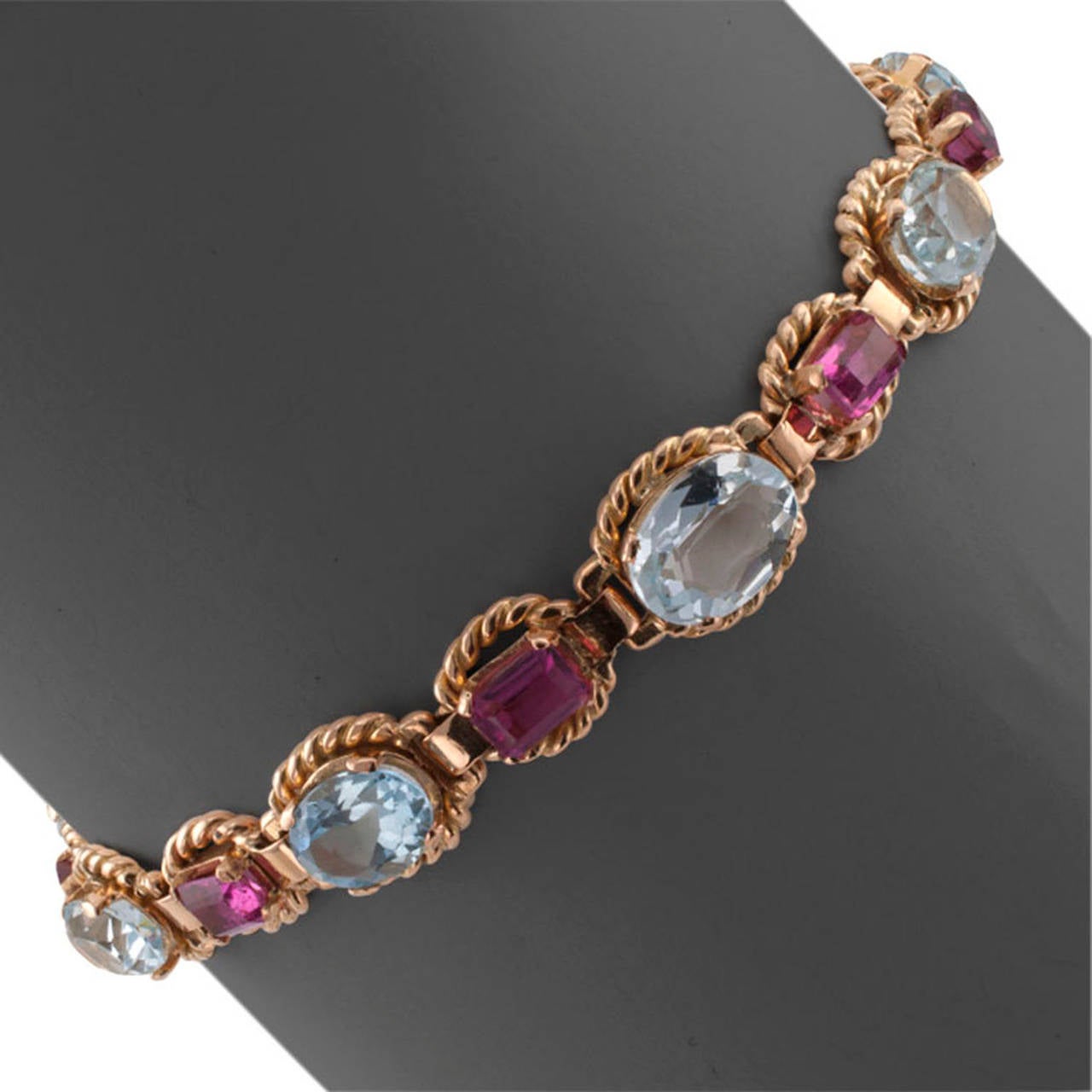 Aquamarine and Pink Tourmaline 18 Karat Gold Bracelet, circa 1950,  features a striking color combination between nine oval-shaped aquamarines alternating with eight rectangular pink tourmalines, each individually framed in corded gold with