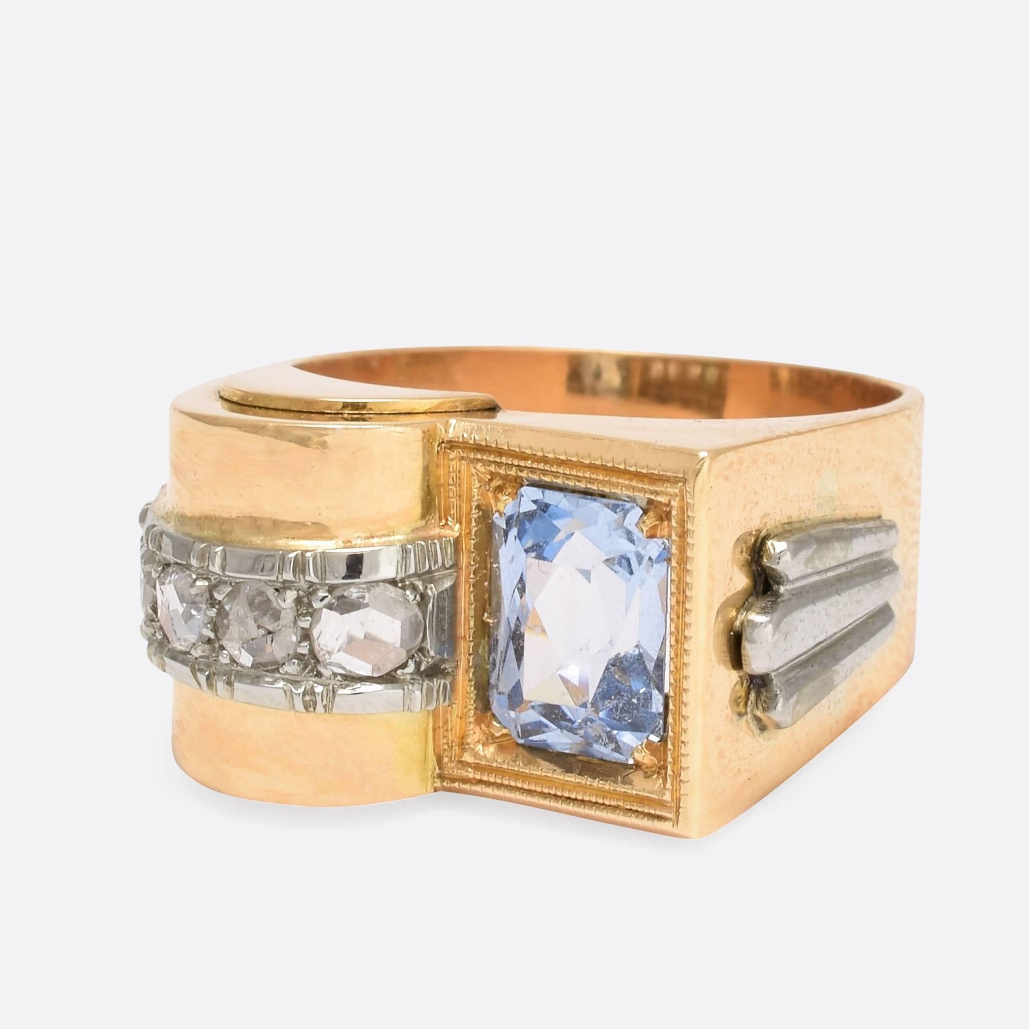 This vintage aquamarine cocktail ring is extremely stylish, and very modernist in design with arches, right-angles, and hints of the preceding Art Deco era. The main stone is a rectangular aquamarine, framed in millegrain, with a row of rose cut