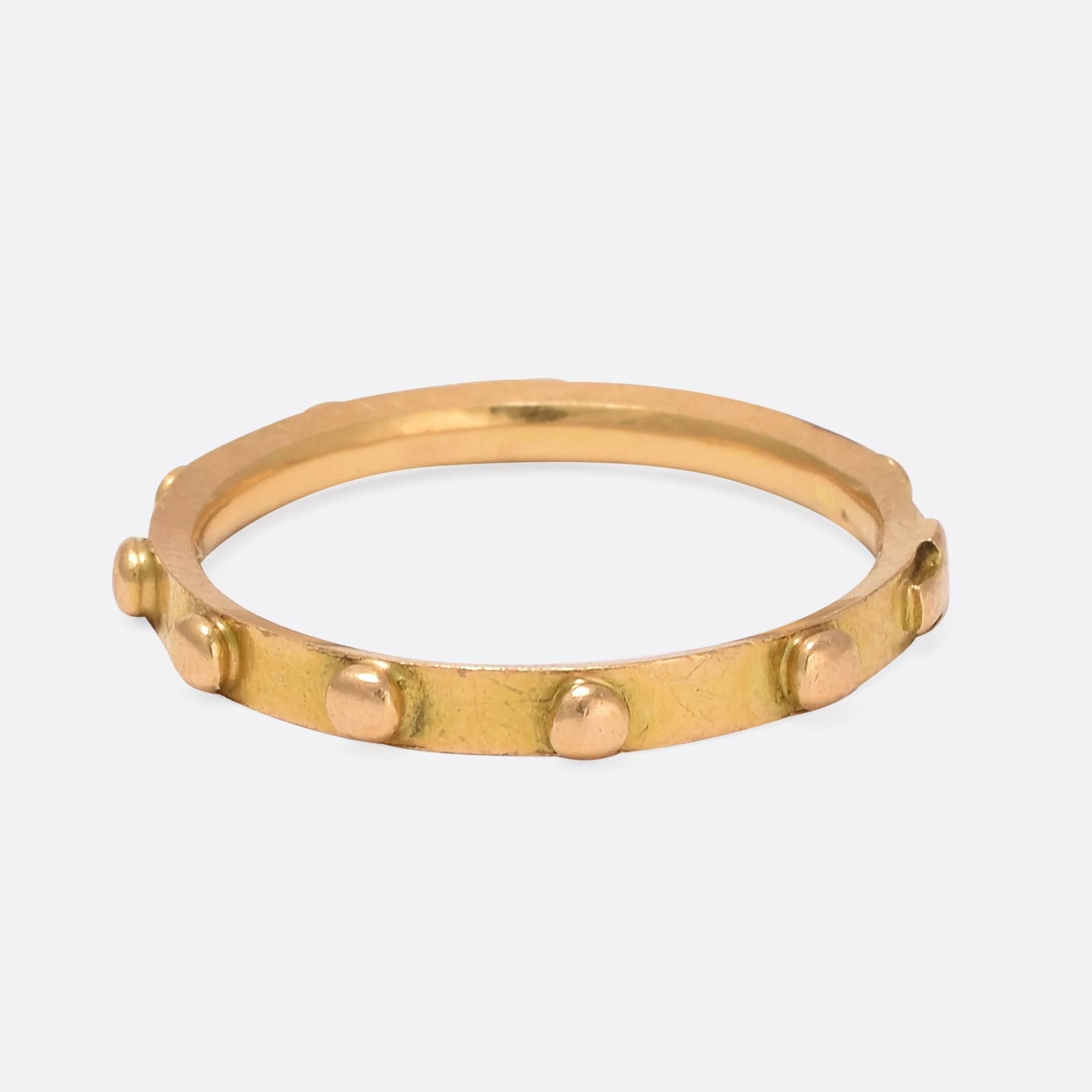 This antique rosary ring features a cross, along with ten studs - representing the one decade of a rosary. It likely belonged to a priest or a nun, and has been well used, with some wear to the cross and studs. Modelled in 15ct yellow gold, it dates