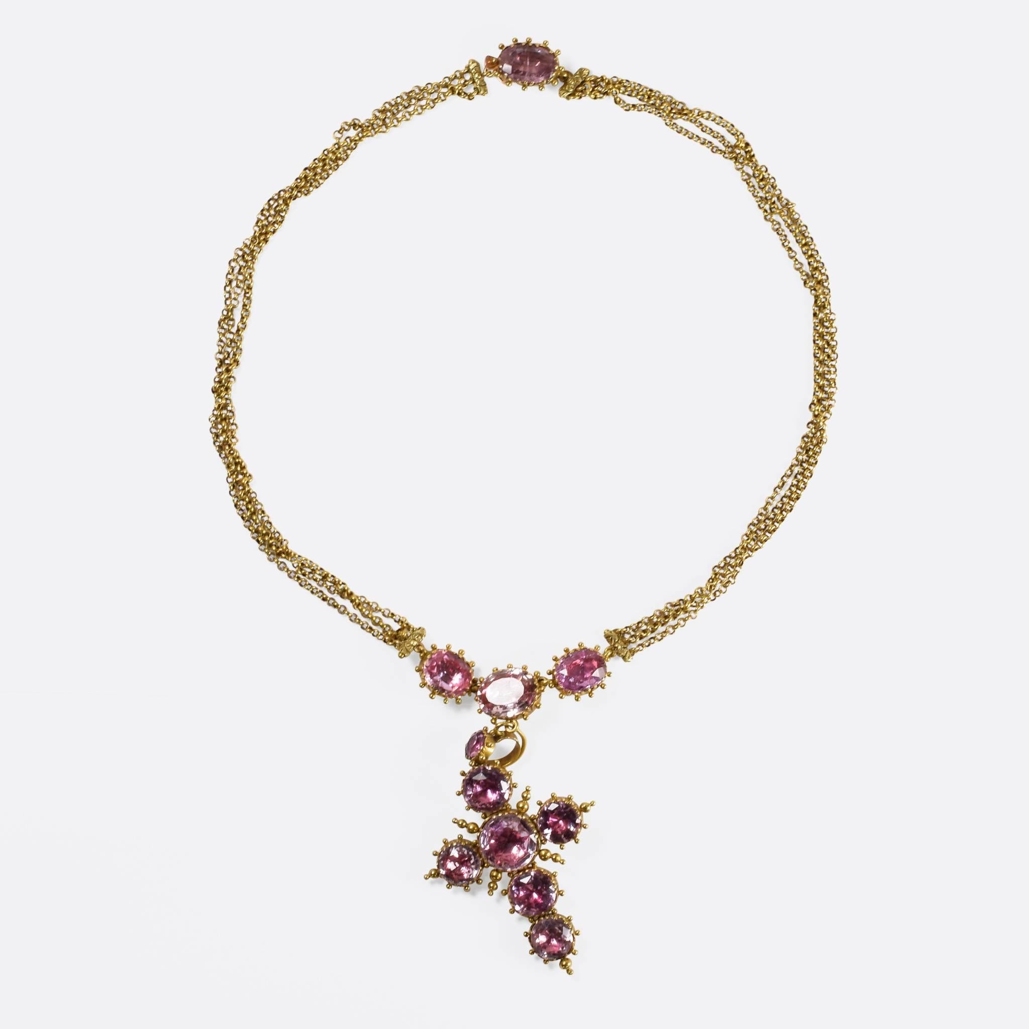 This stunning 18th Century necklace features a large cross pendant, lavishly set with pink topaz stones in closed foil-back settings. Dating to c.1780, the chain is composed of three distinct strands, all modelled in 15ct gold - the settings adorned