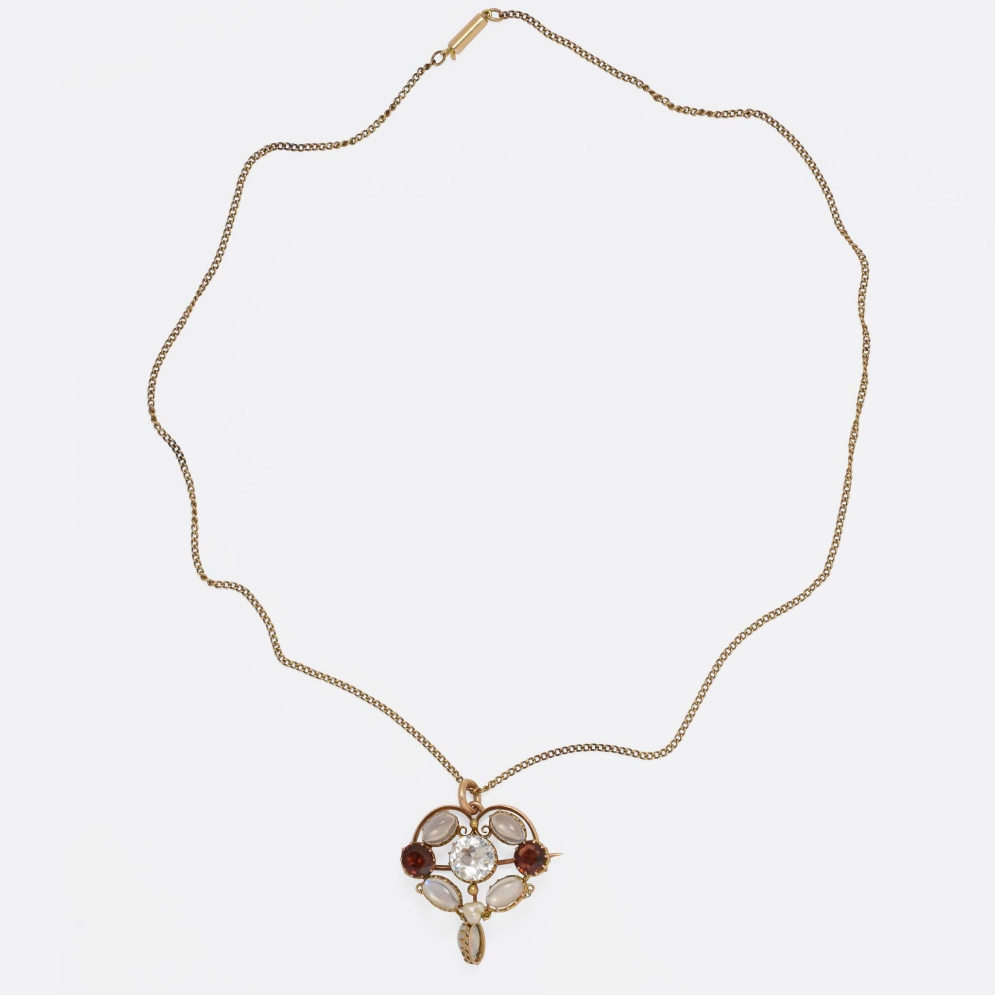 This superb necklace has the shape of a stylised heart - set with a lovely combination of blue moonstone, garnet and baroque pearl, all around a beautiful pale aquamarine. It was made in the 1920s and is modelled in 9ct gold, with fittings for wear