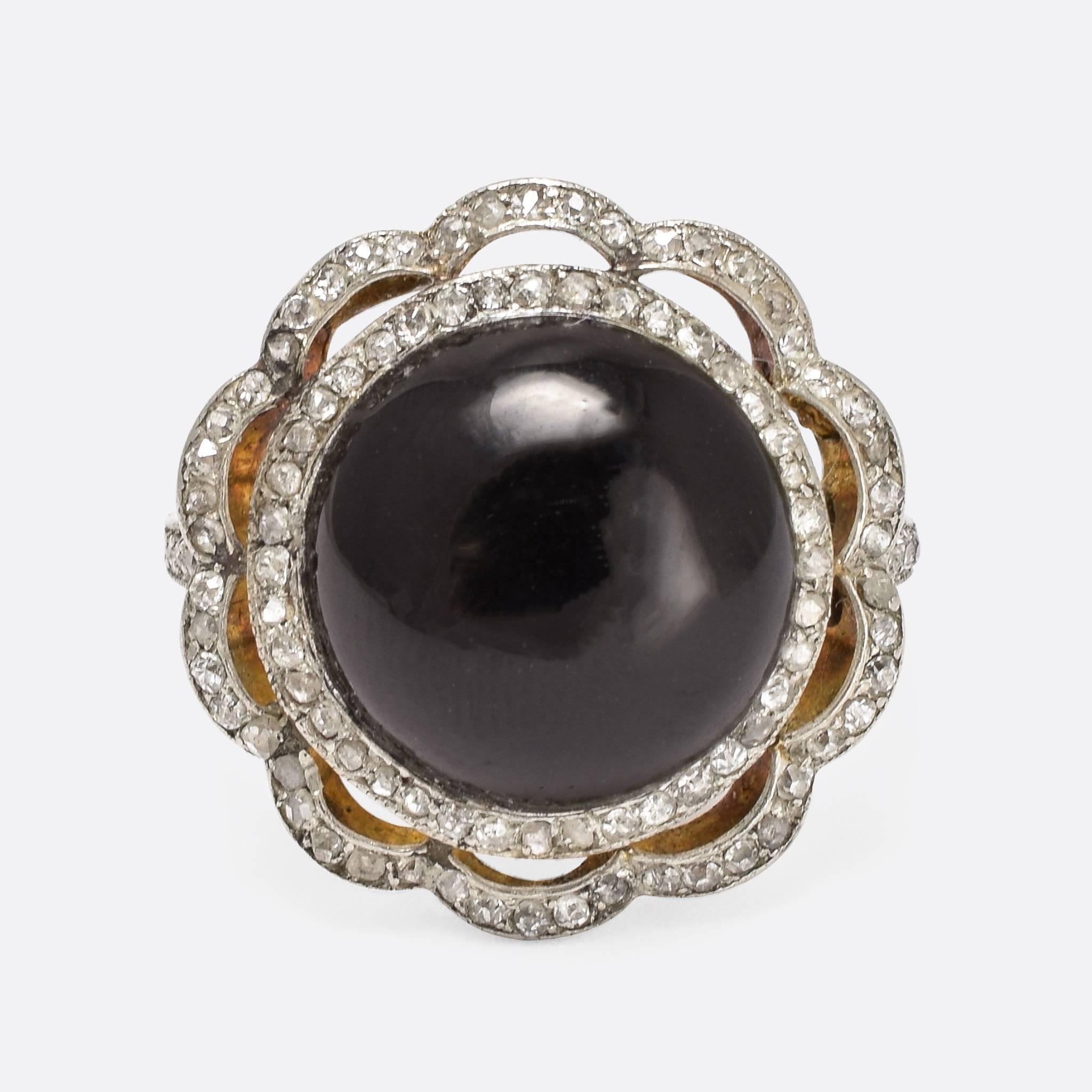 This fabulous antique cocktail ring was made in France in the early 20th Century. It is set with a large onyx cabochon in the centre, surrounded by two rows of rose cut diamonds in millegrain platinum settings. The bezel displays wonderful leaf and