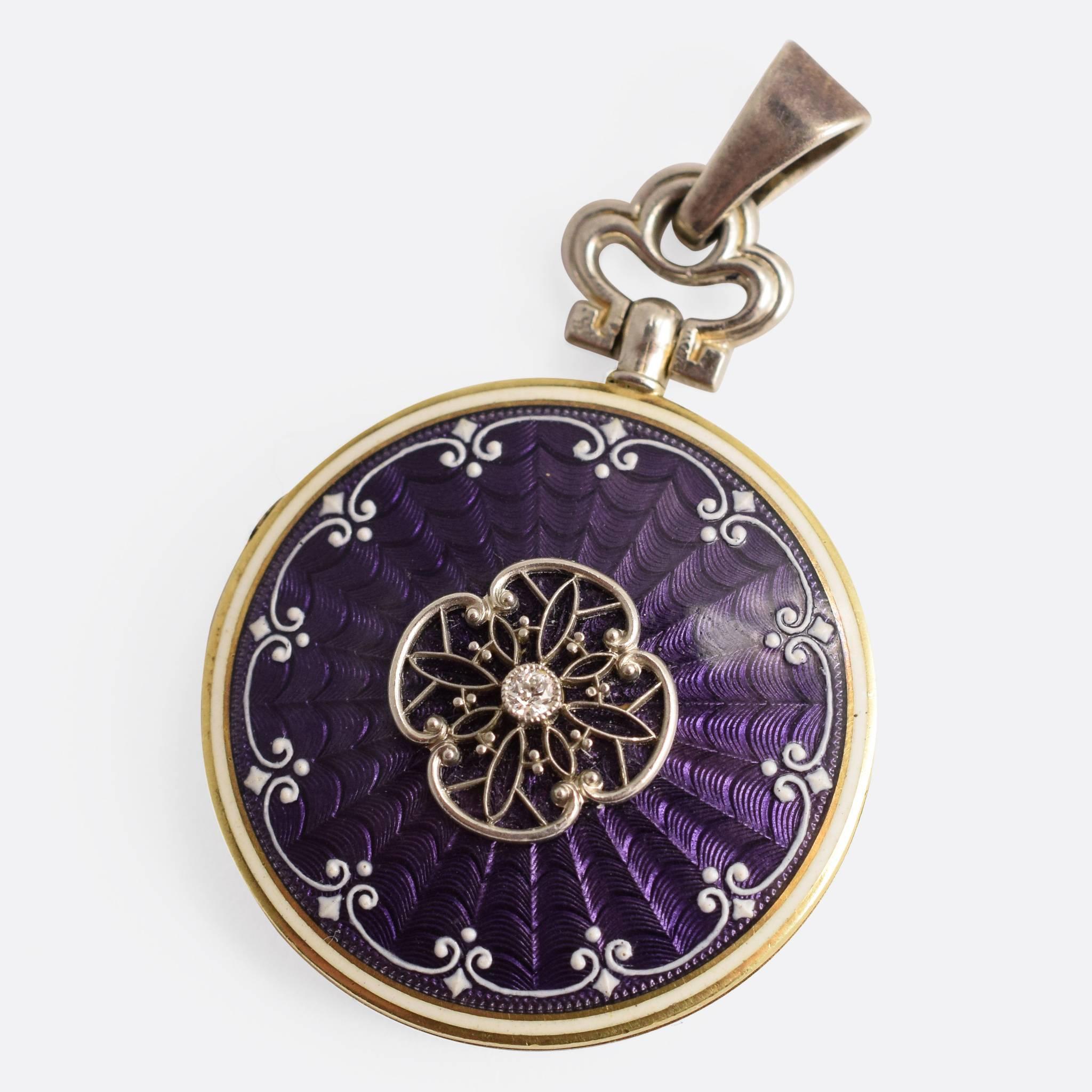 This stunning Edwardian era locket features exquisite guilloché enamelling to the front and back, in a rich purple colour. An ornate white border raises slightly above the surface, and in the centre lies a single old cut diamond. An inscription