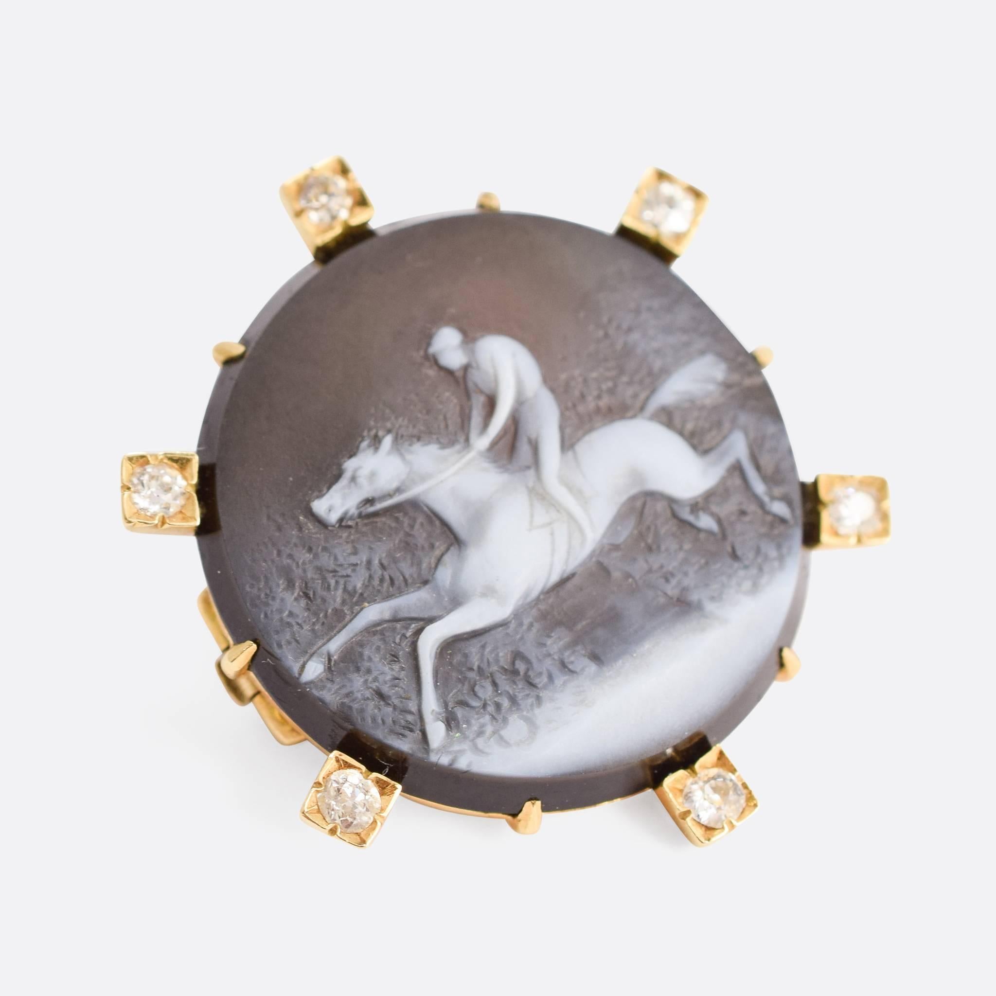 This wonderful antique brooch is set with an onyx cameo, carved to depict a galloping horse with rider. Modelled in 18ct gold, the piece has six old cut diamonds framing the central image.